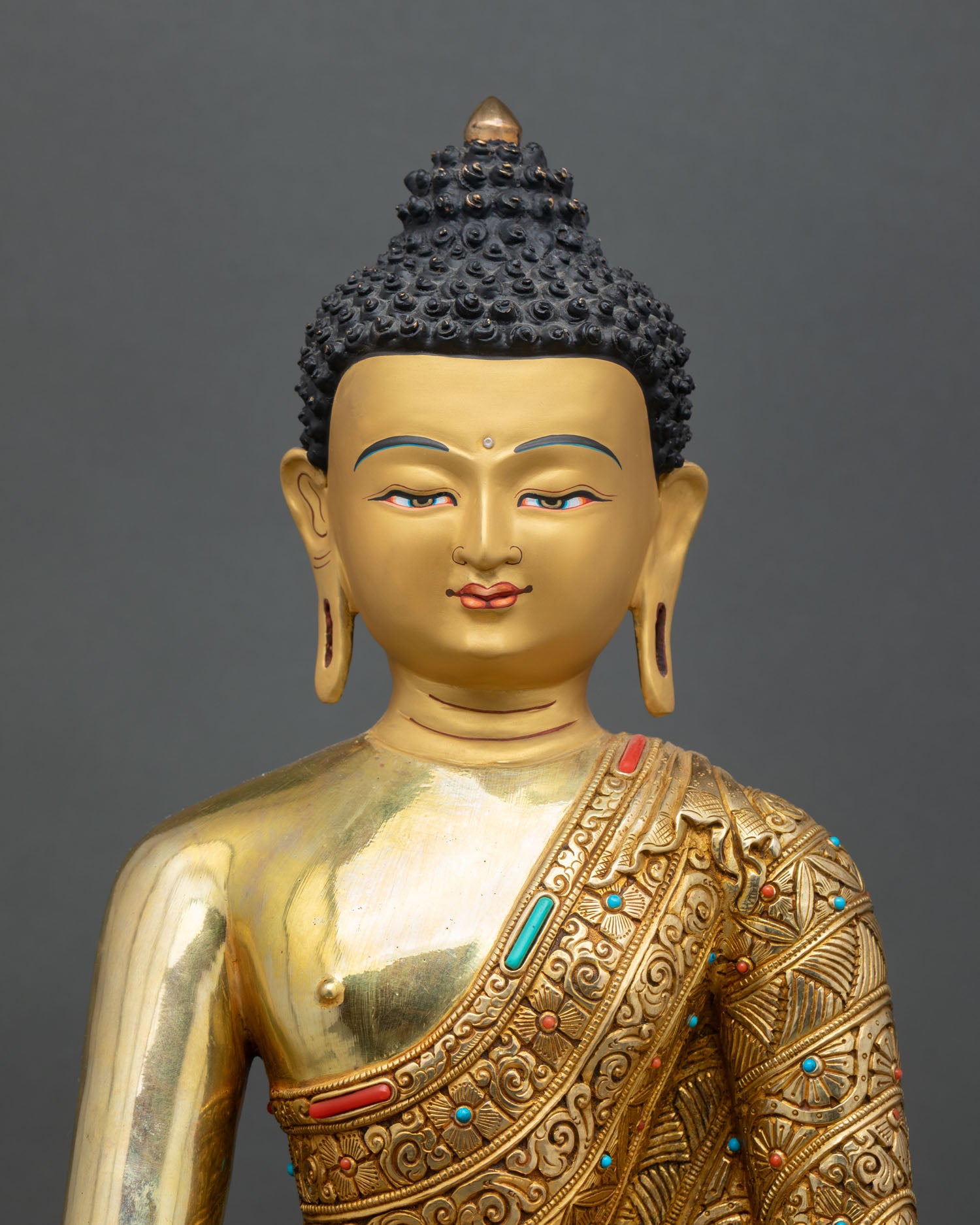 Close up of handcrafted Shakyamuni Buddha idol with detailed robe and gold accents