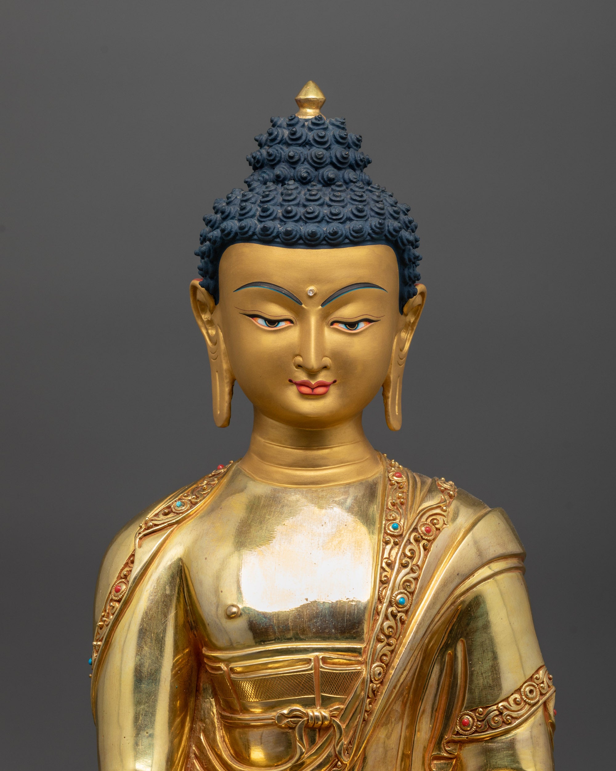 Close up of intricate carvings and semi-precious stones on the monk’s robe of Buddha statue