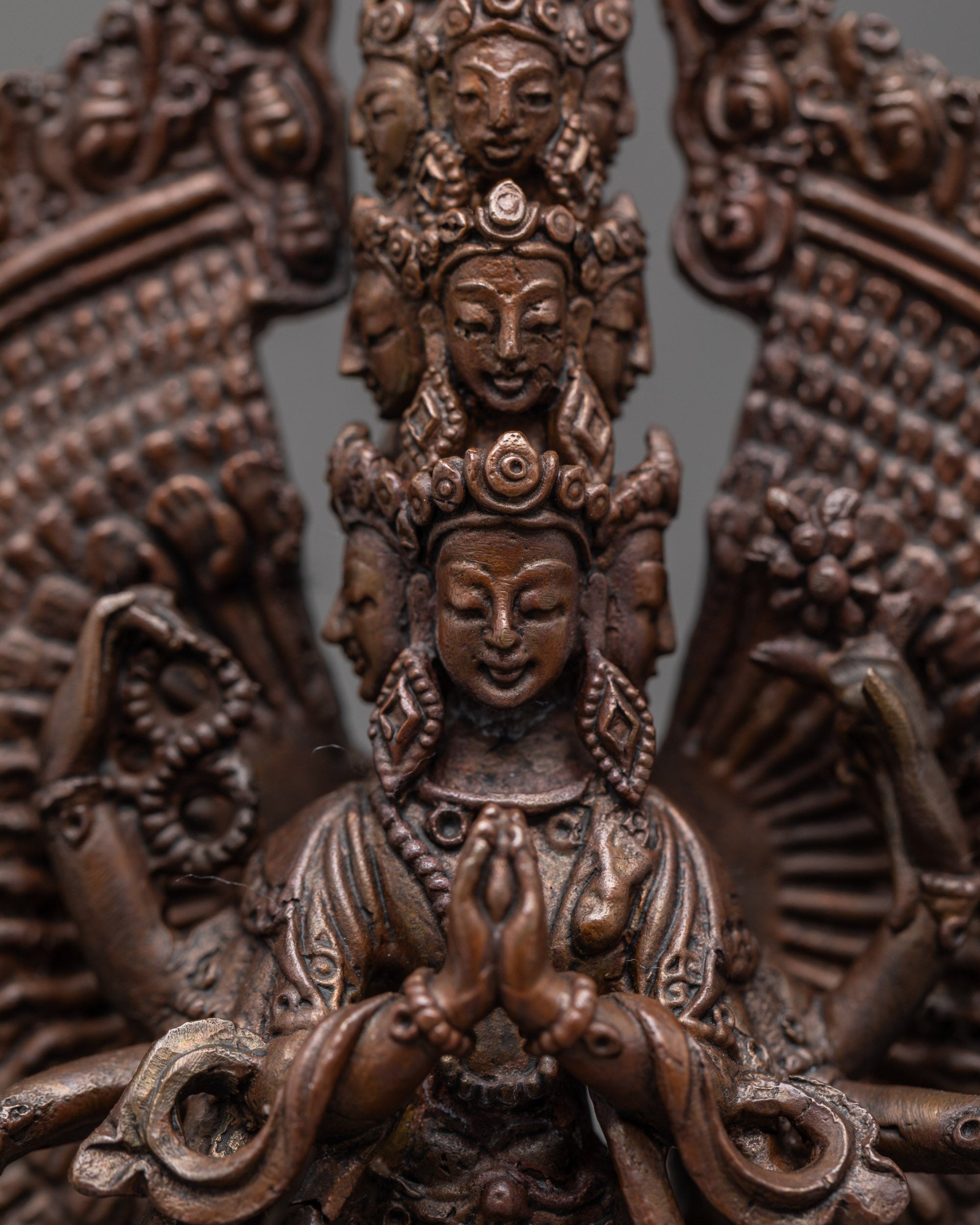 Close up of oxidized copper face and hands holding sacred symbols on Chenrezig statue