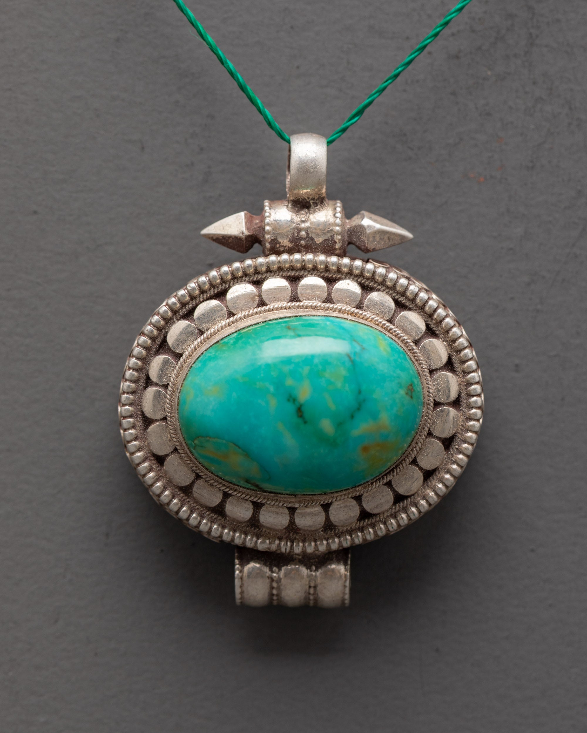 Close up of pure silver locket showing bold turquoise stone and intricate carving details