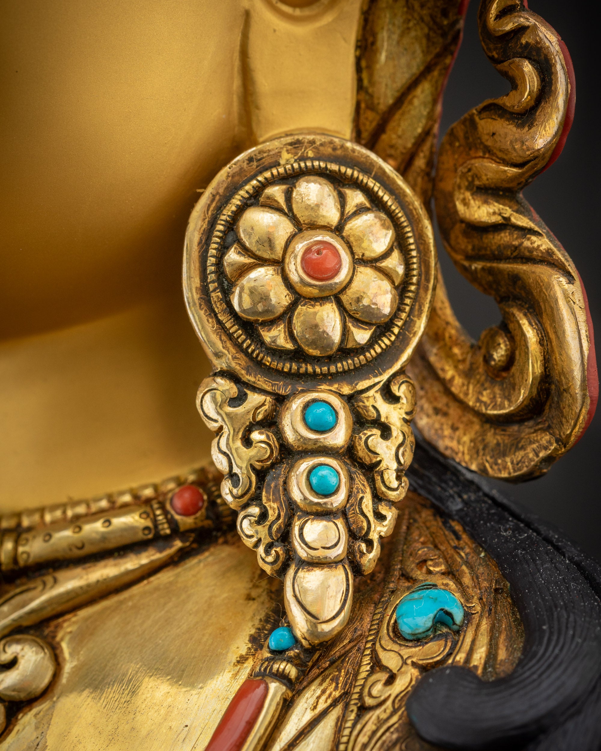 Close up of statue earrings right side with floral motif and gemstone inlay