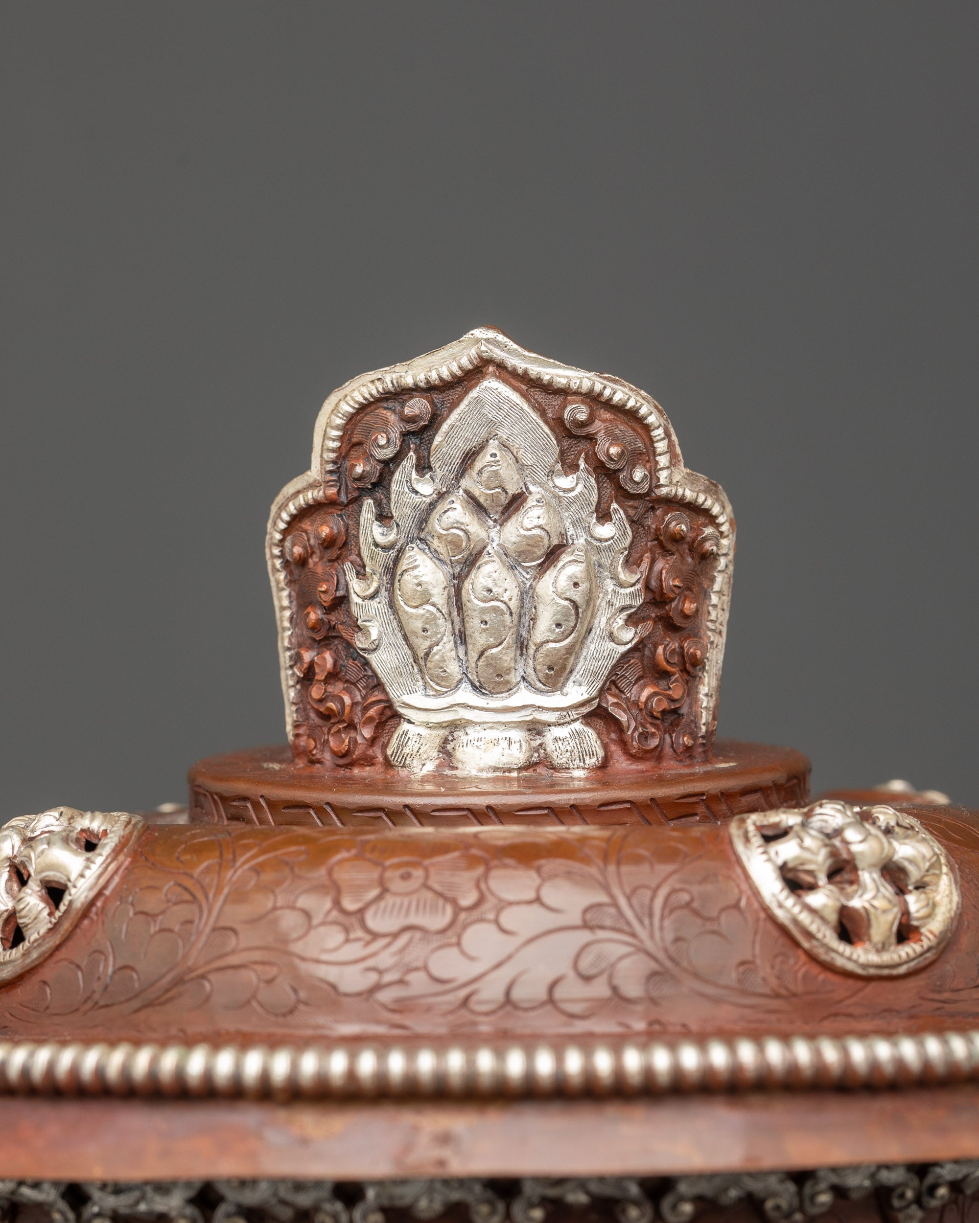 Close up oxidized Tibetan butter lamp with detailed spiritual carvings and steady flame