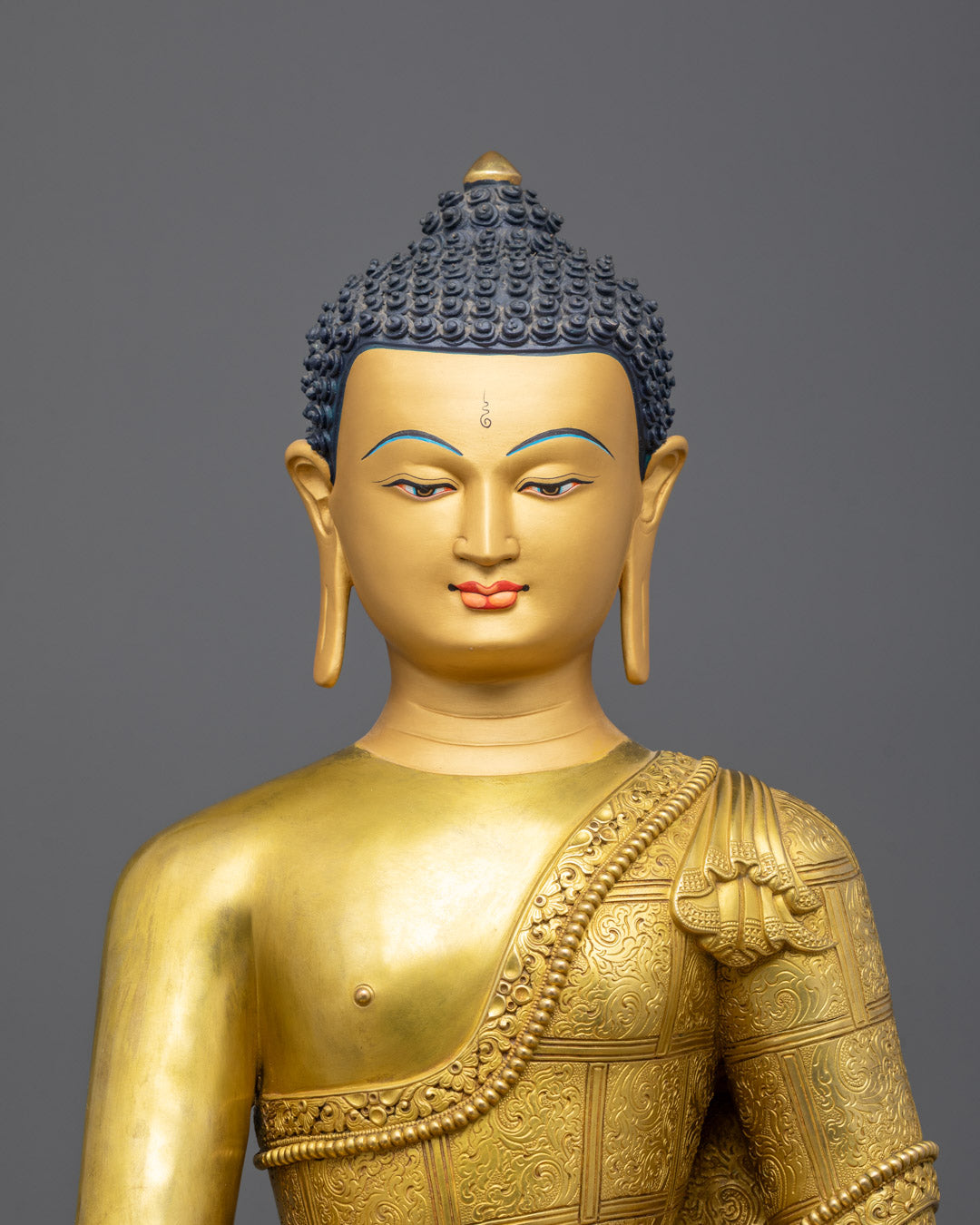 Closeup of Shakyamuni Buddha gold face and intricate robe carvings
