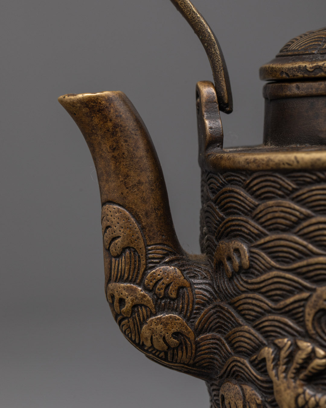 Closeup of intricate dragon carving on handcrafted Tibetan brass bronze tea pot