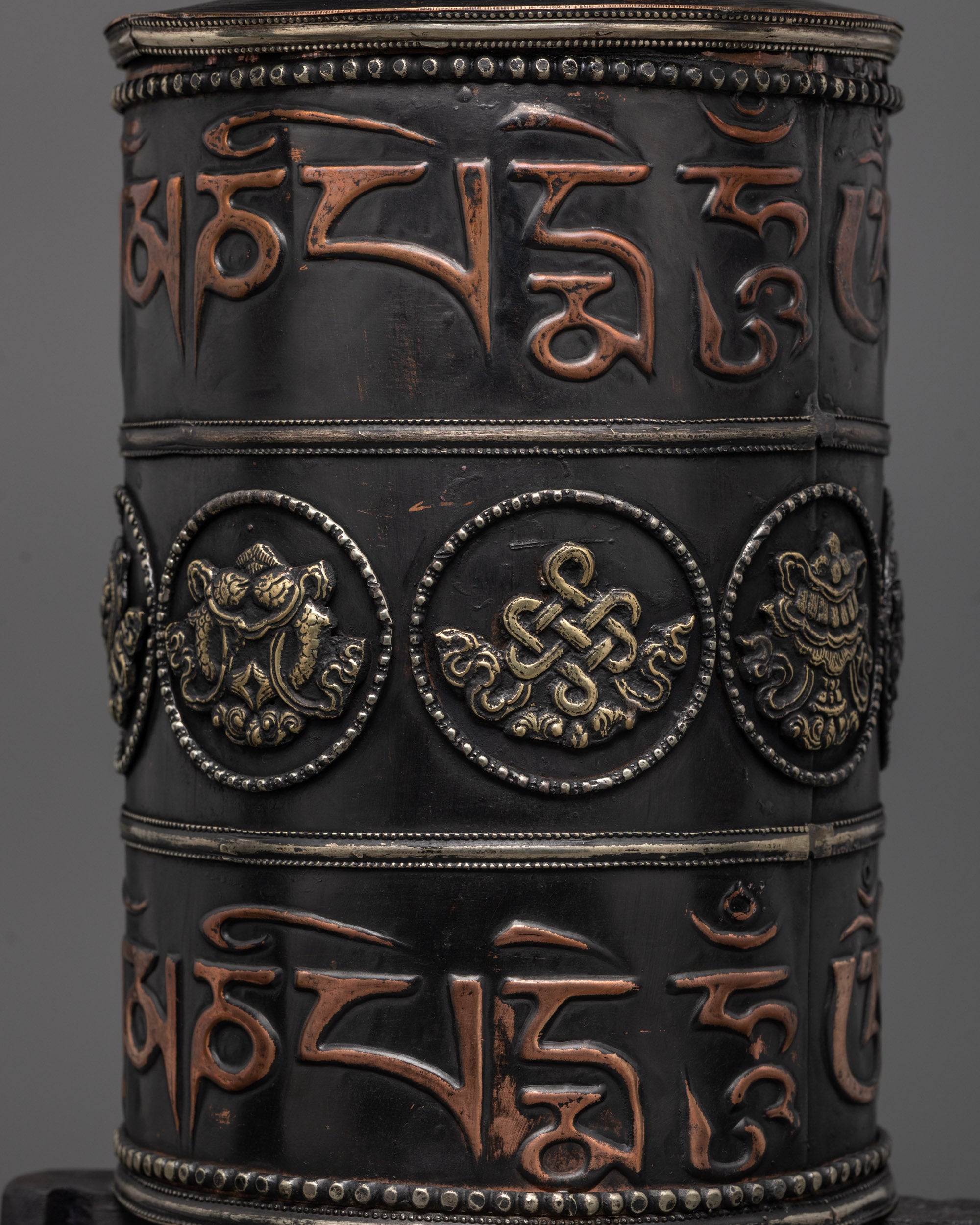 Dark wood-framed prayer wheel featuring engraved spiritual symbols and motifs