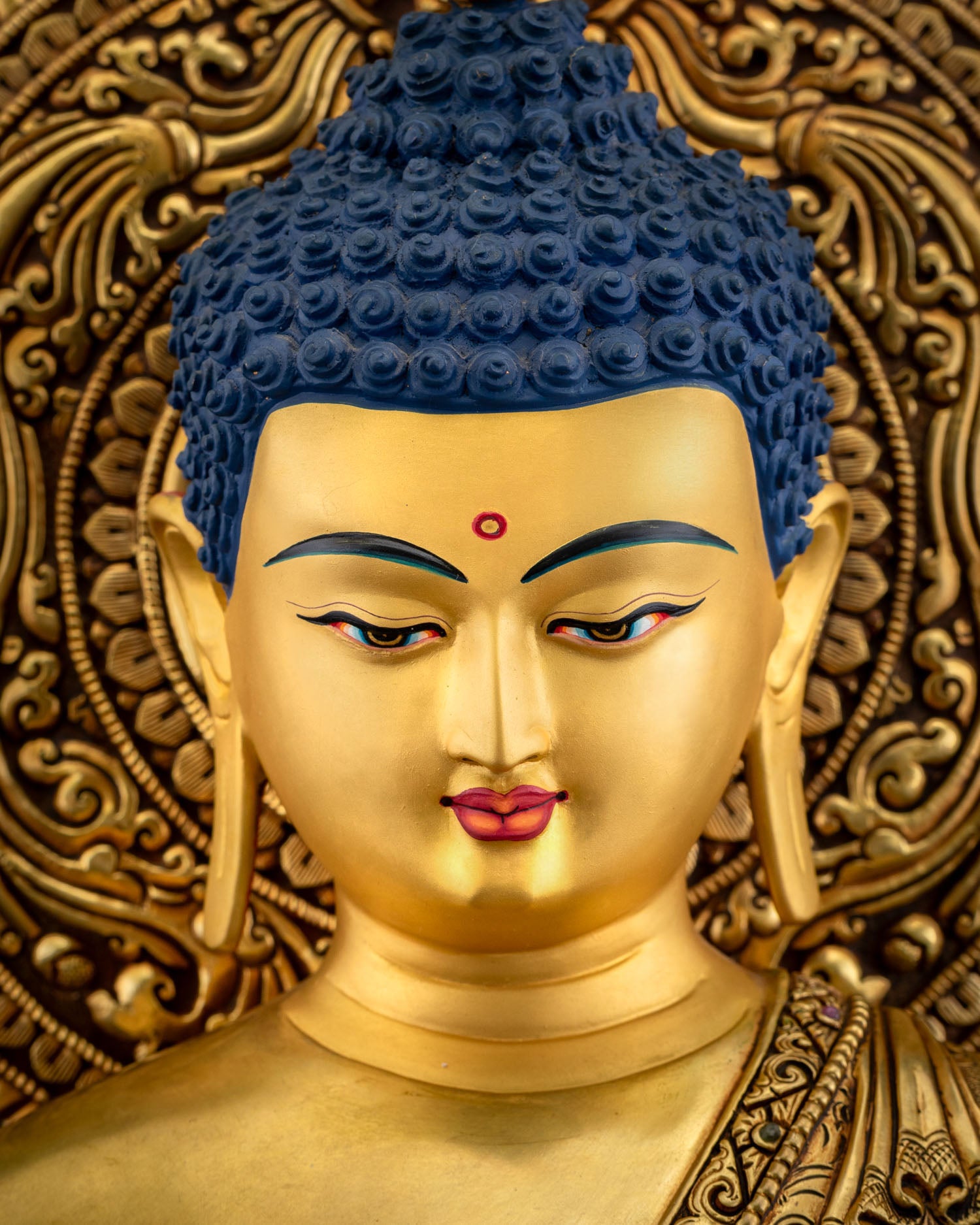 Detailed close up of Bhaisajyaguru face with serene expression, blue curled hair, and radiant 24K gold paint