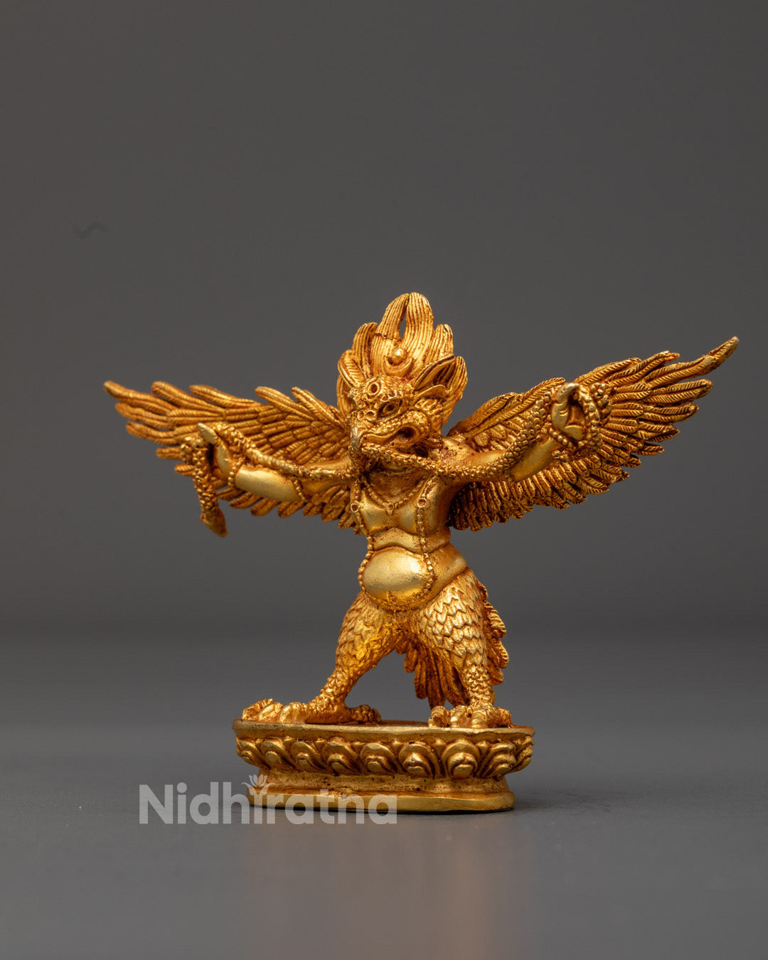 Detailed carving on the chögu robe and wings of the Buddhist Garuda protector sculpture, painted with vibrant acrylic colors