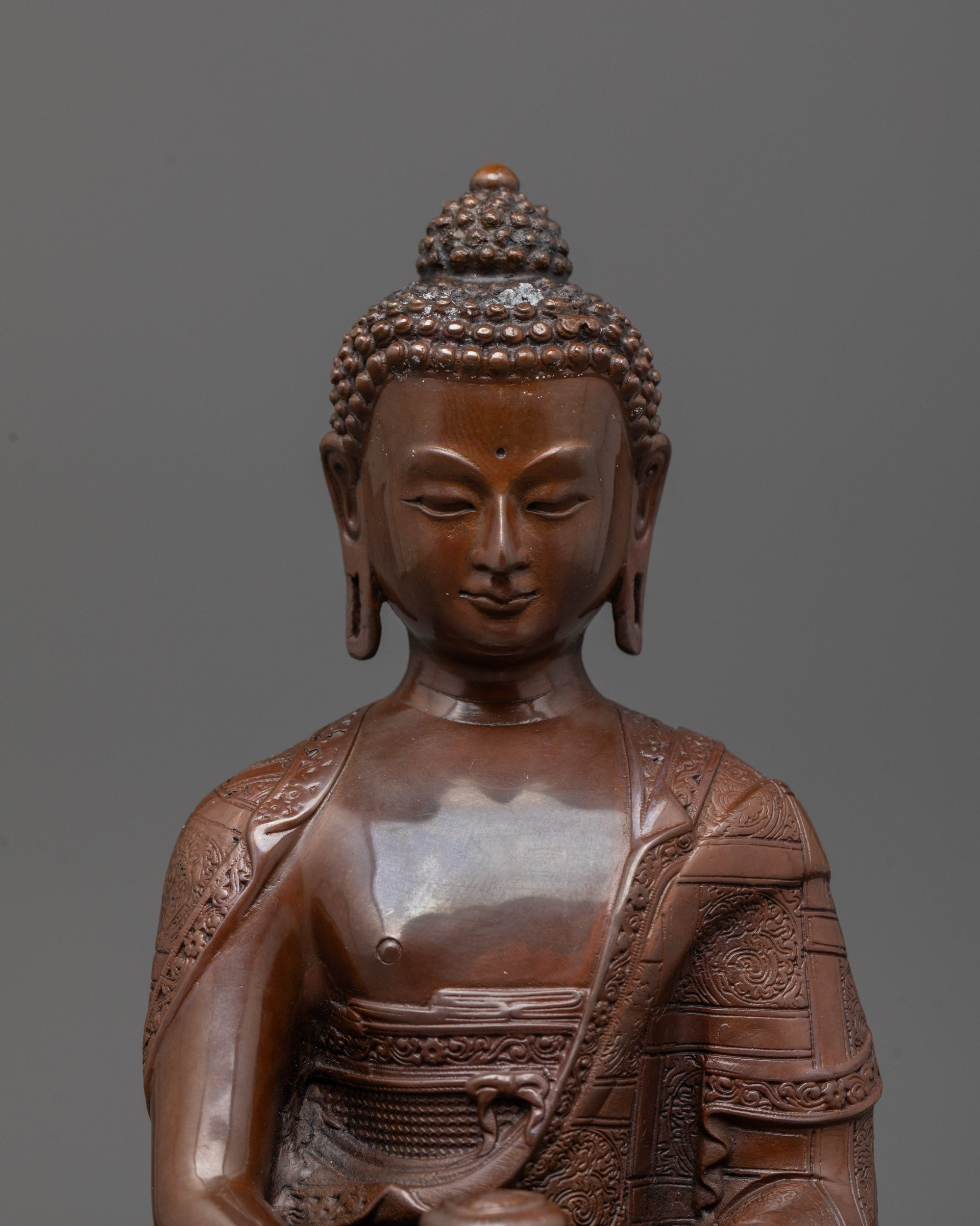 Detailed close-up of Amitabha Buddha’s peaceful face with gold gilded finish