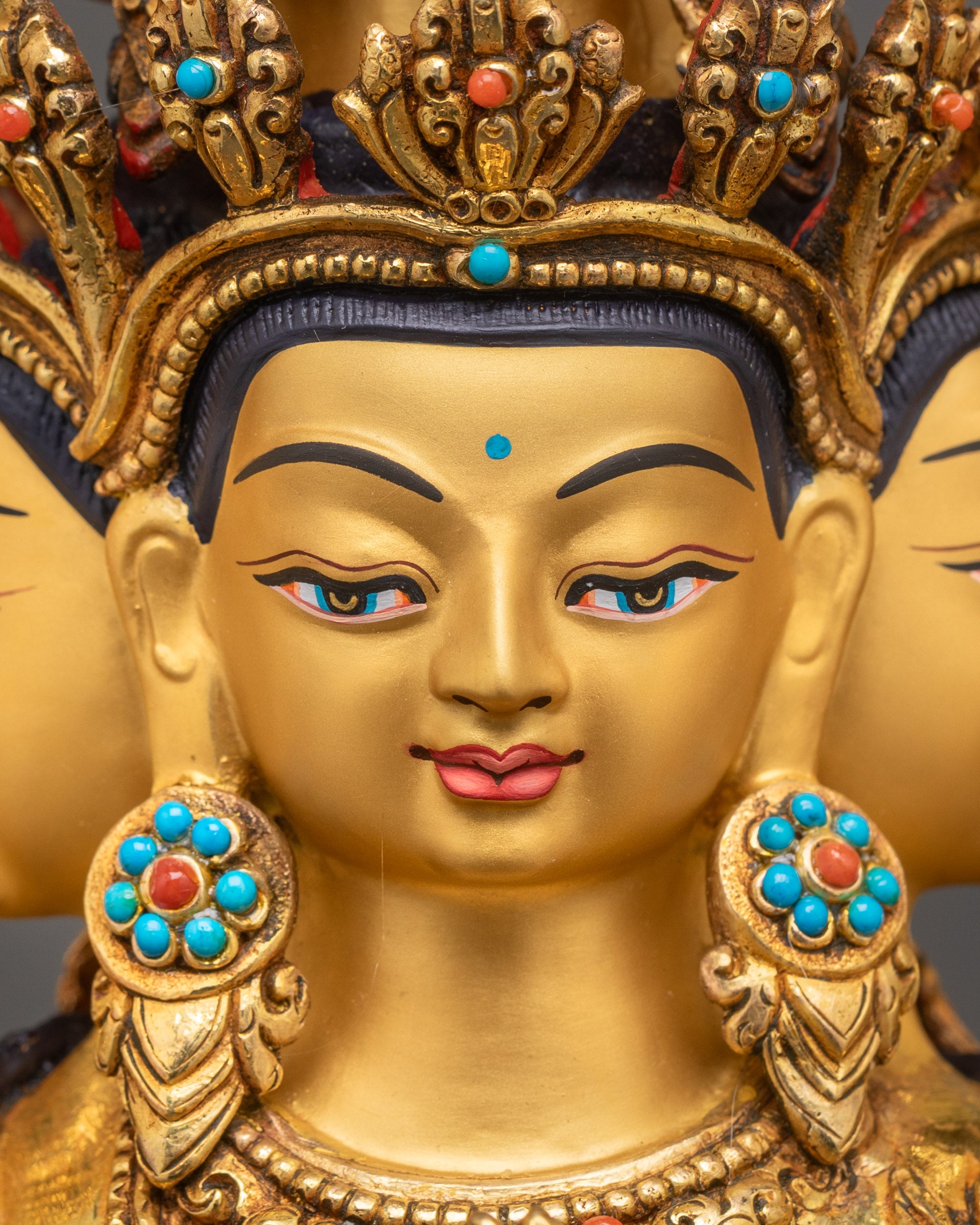 Detailed close-up of Chenrezig Bodhisattva face, 24K gold-painted features with serene expression, Nepalese copper fire-gilded statue