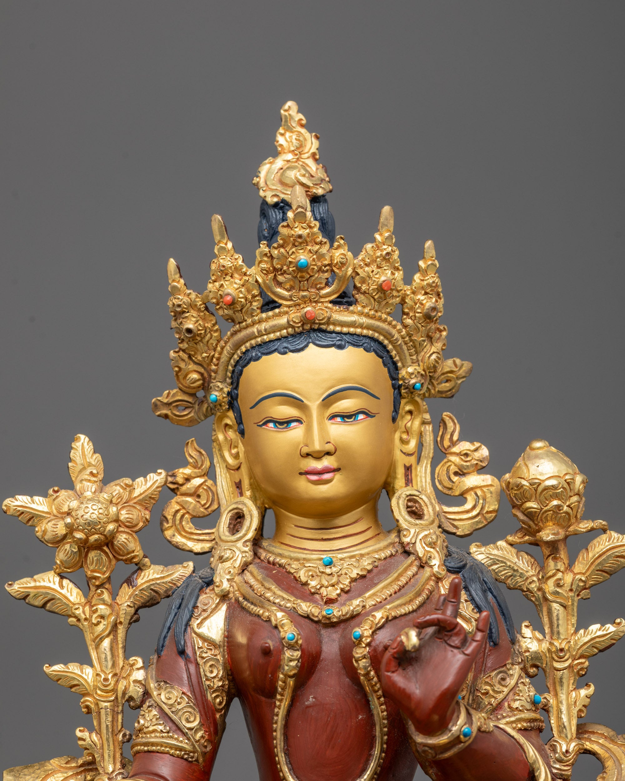 Detailed close-up of Green Tara statue’s radiant 24k gold gilded face