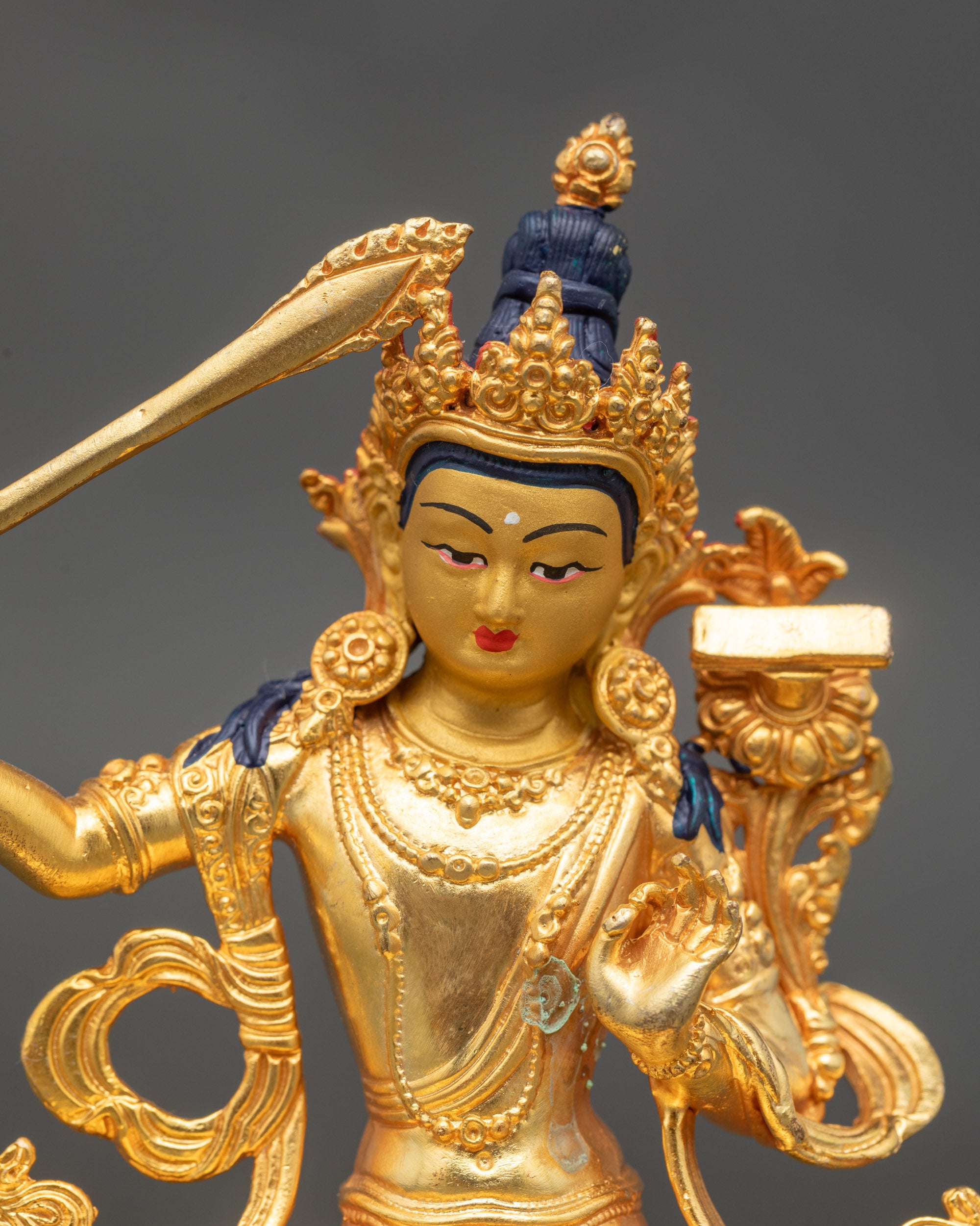 Detailed close-up of Manjushri face with gold paint and serene focused expression
