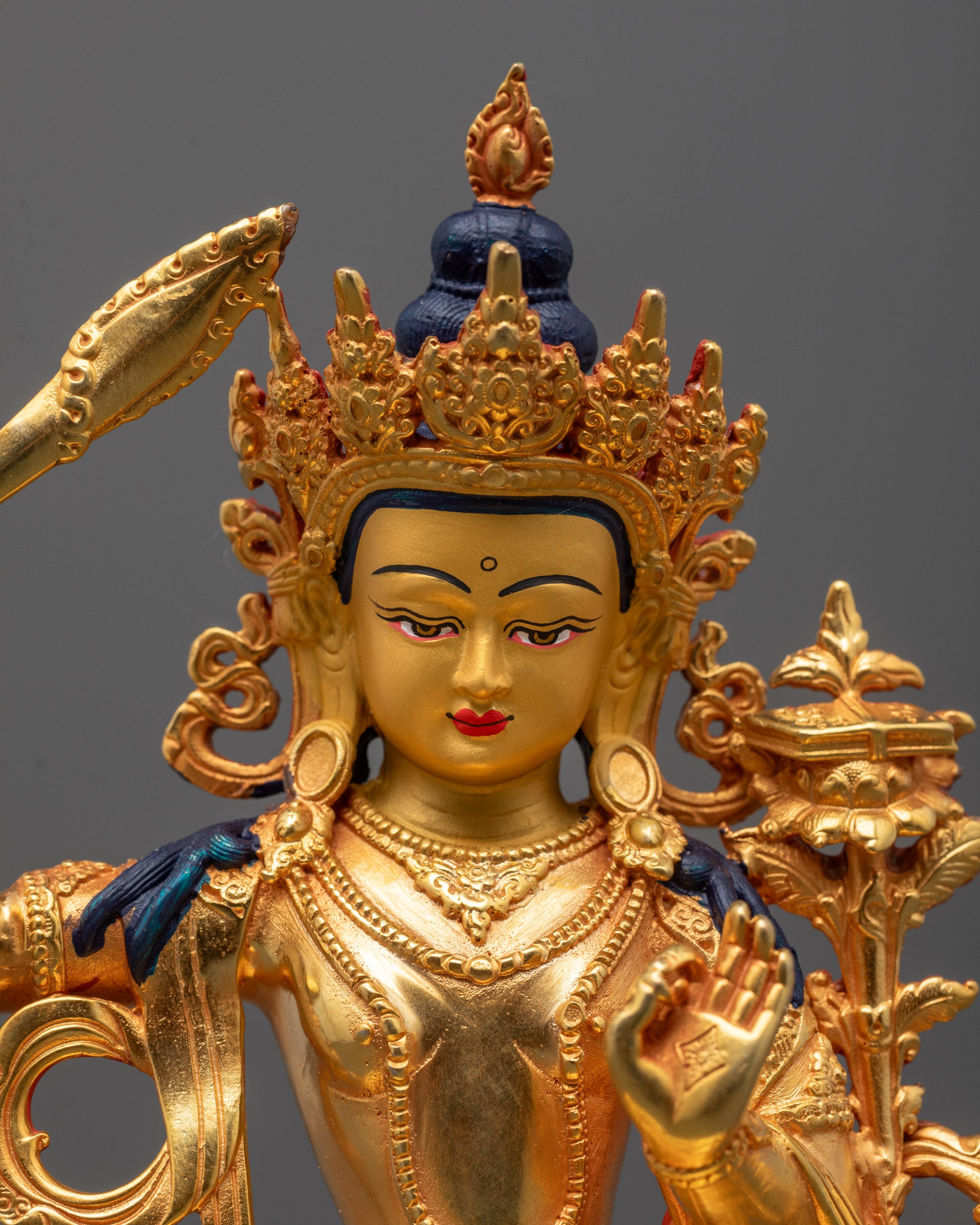 Detailed close-up of Manjushri’s face and sword in machine-crafted Buddhist sculpture
