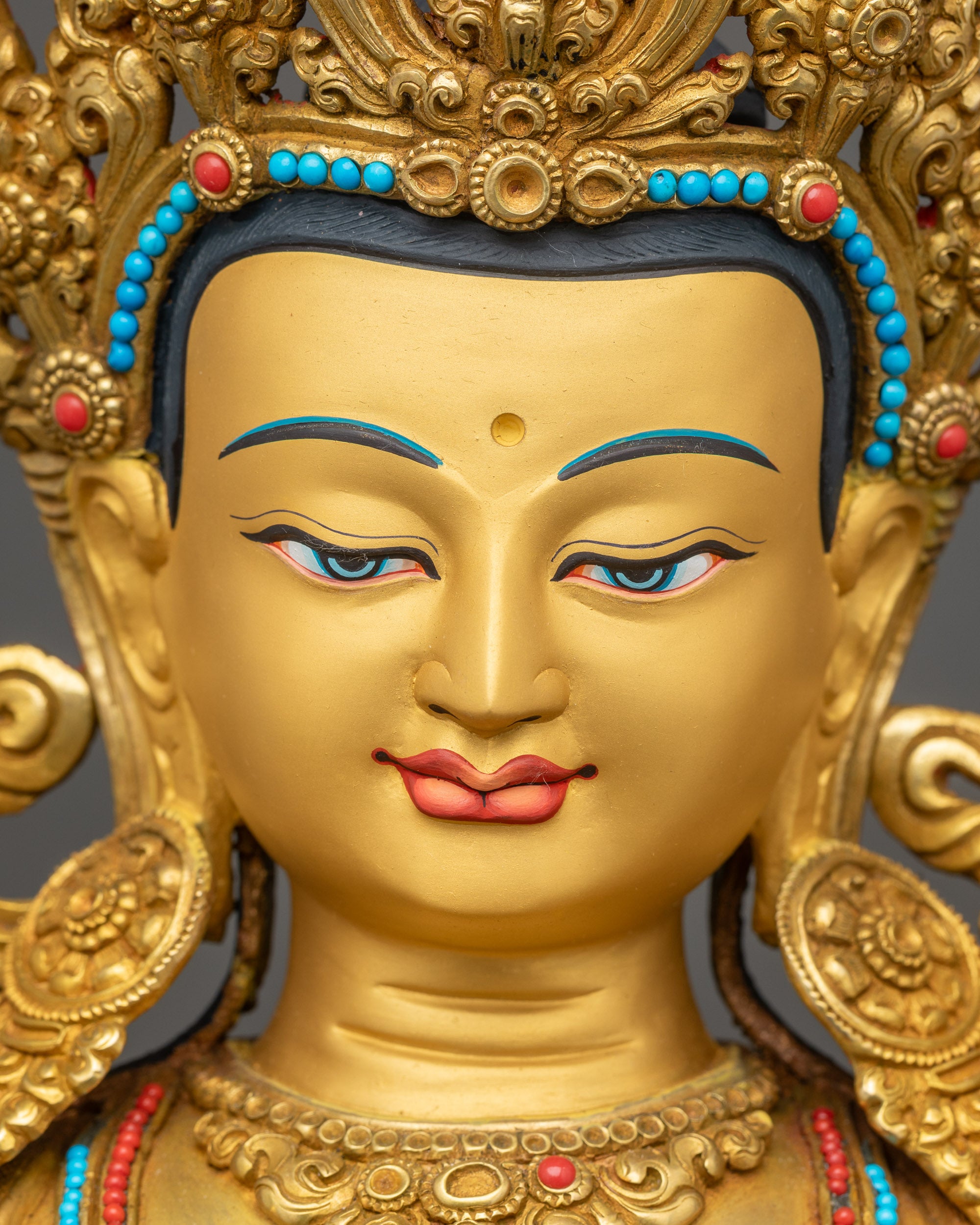 Detailed close-up of Manjushri statue face with peaceful expression and gold-gilded finish