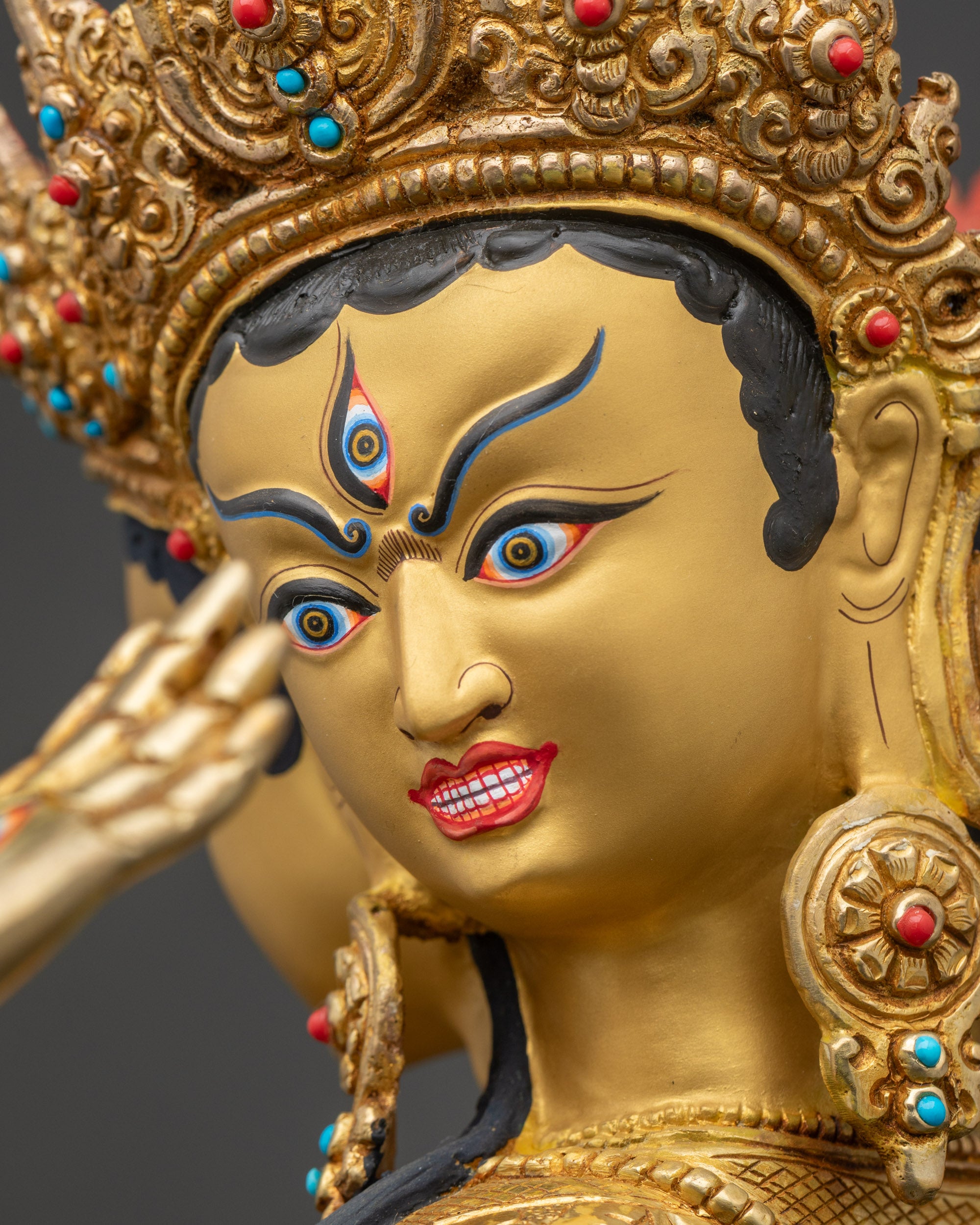 Detailed close-up of Namgyalma statue face with three expressive gold-painted heads, symbolizing wisdom and longevity