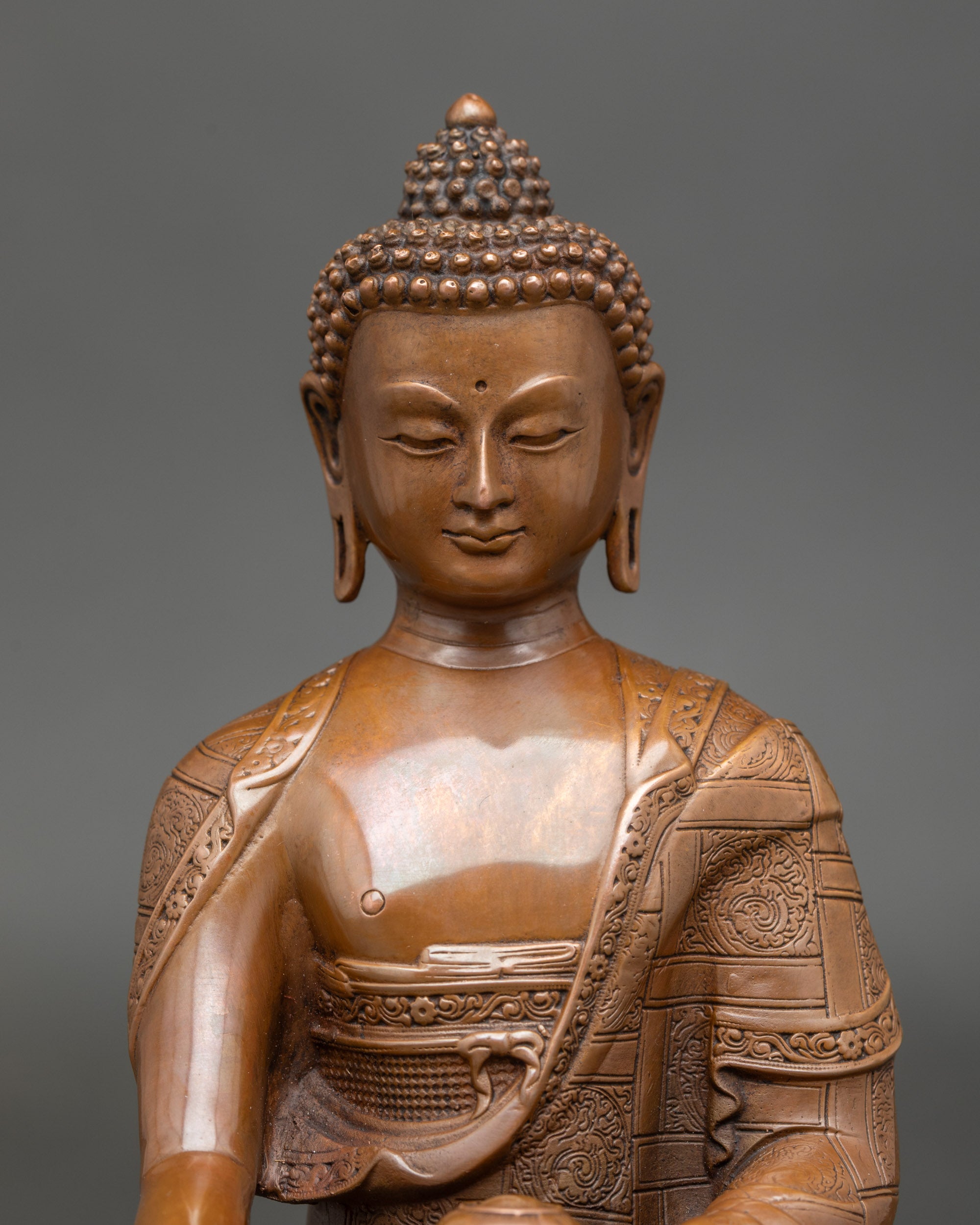 Detailed close-up of Shakyamuni Buddha's face with a serene expression and saffron robes, a machine-made Nepalese meditation statue