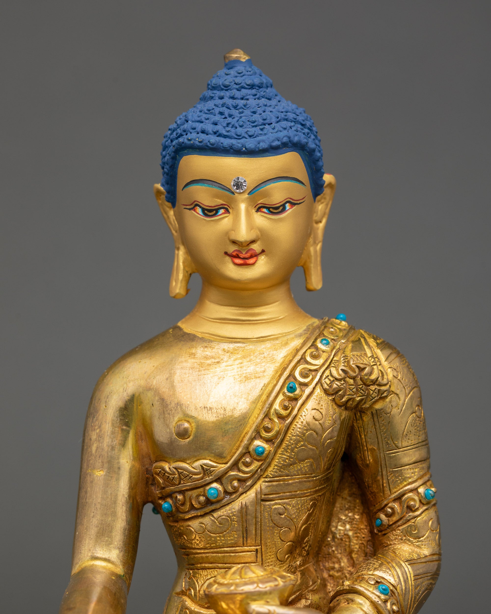 Detailed close-up of gold-painted face of Shakyamuni Buddha sculpture on lotus seat