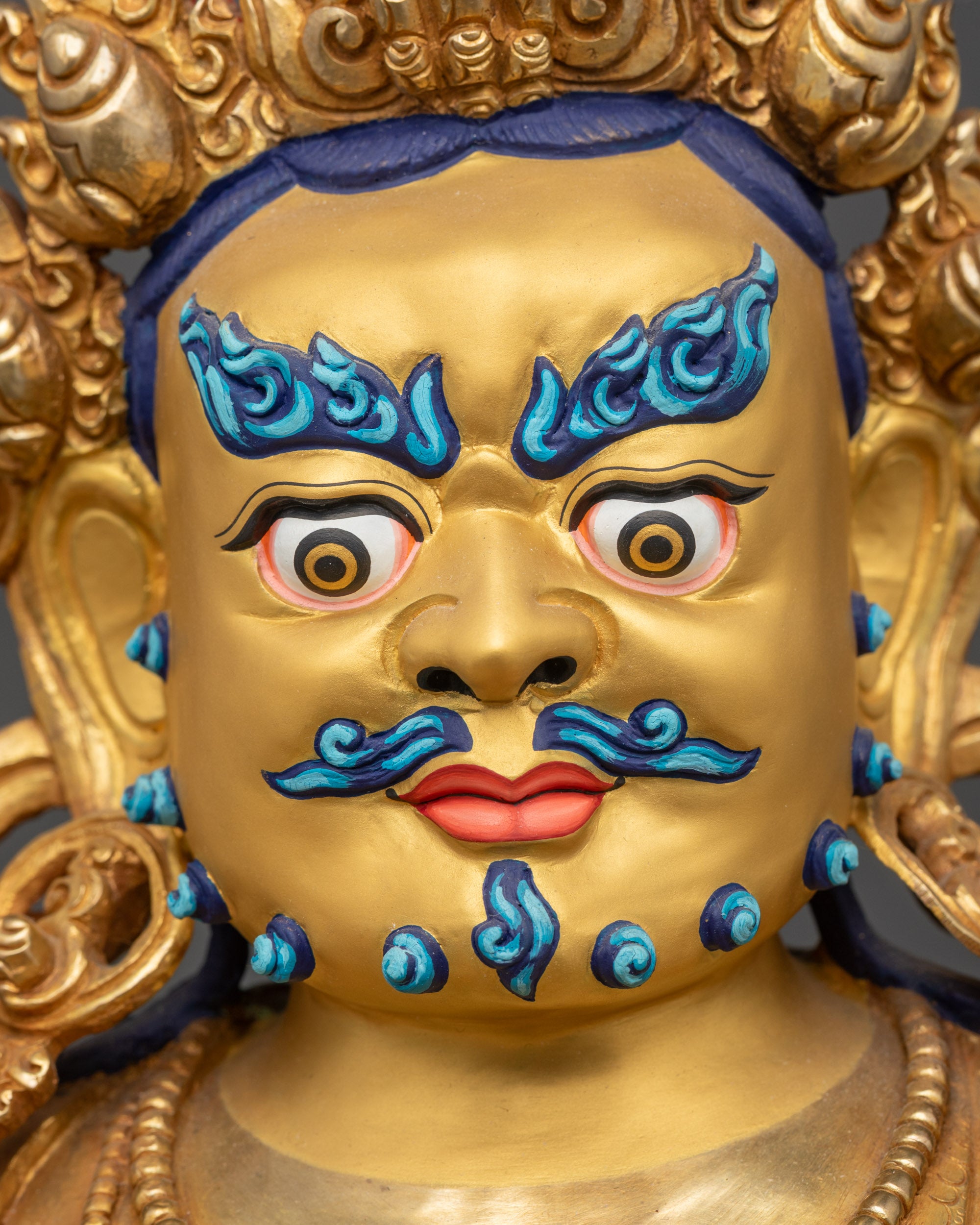 Detailed close up face of Dzambhala Buddha with fierce eyes and blue eyebrows