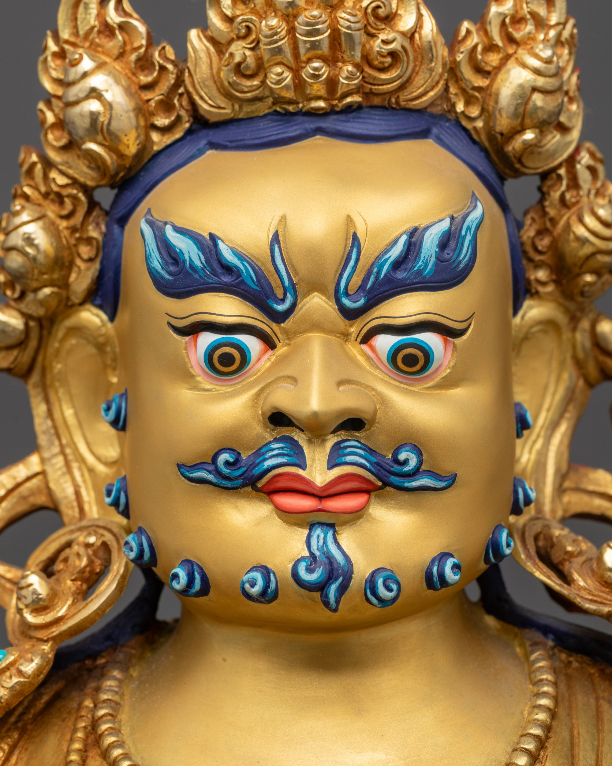 Detailed close up face of Dzambhala with wrathful expression and five-jeweled crown