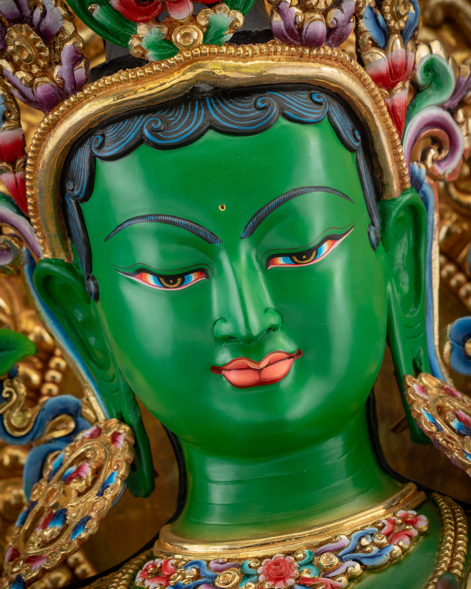 Detailed close up face of Green Tara seated on ornate Tibetan Buddhist throne