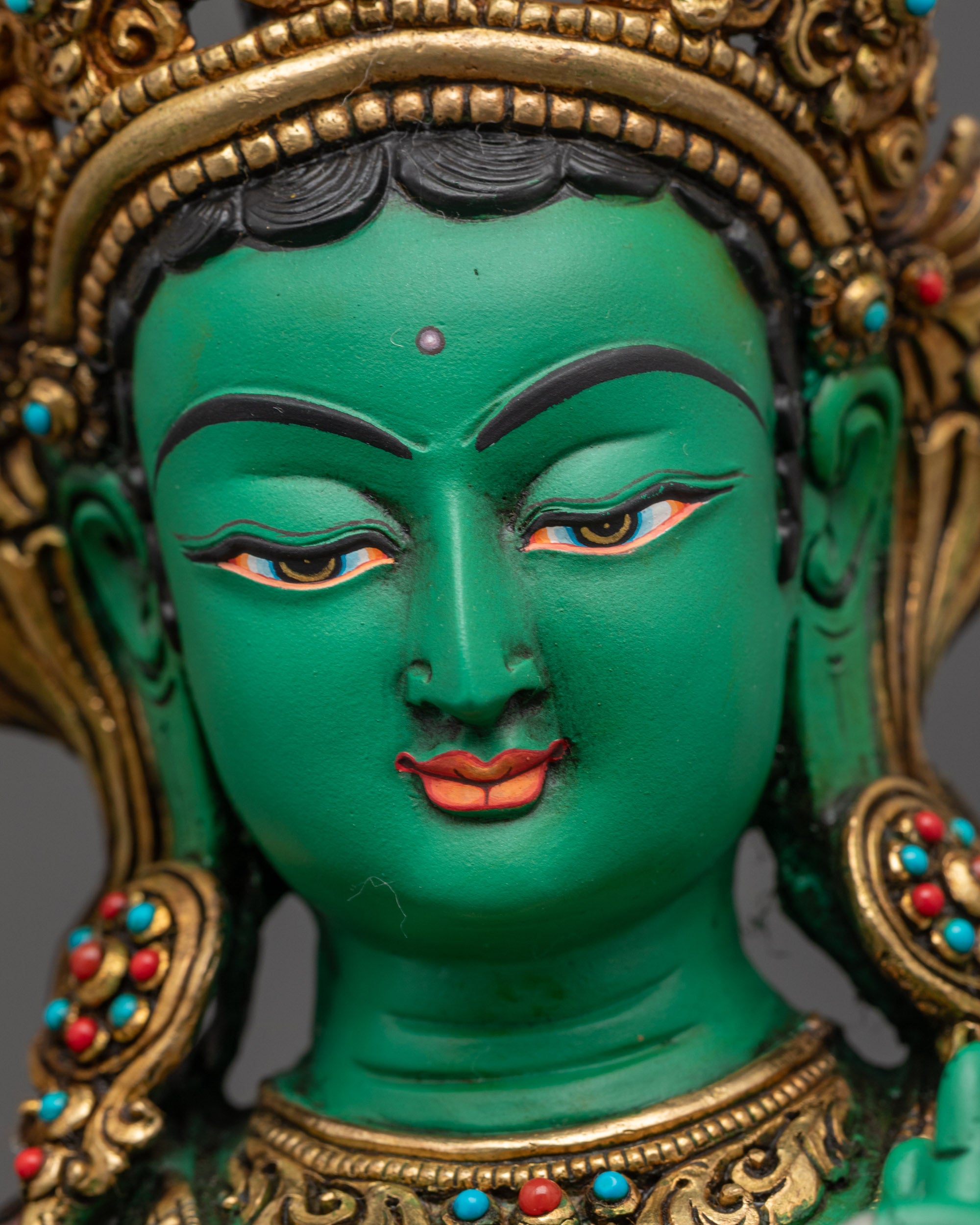 Detailed close up face of Green Tara showing serene expression and jeweled crown