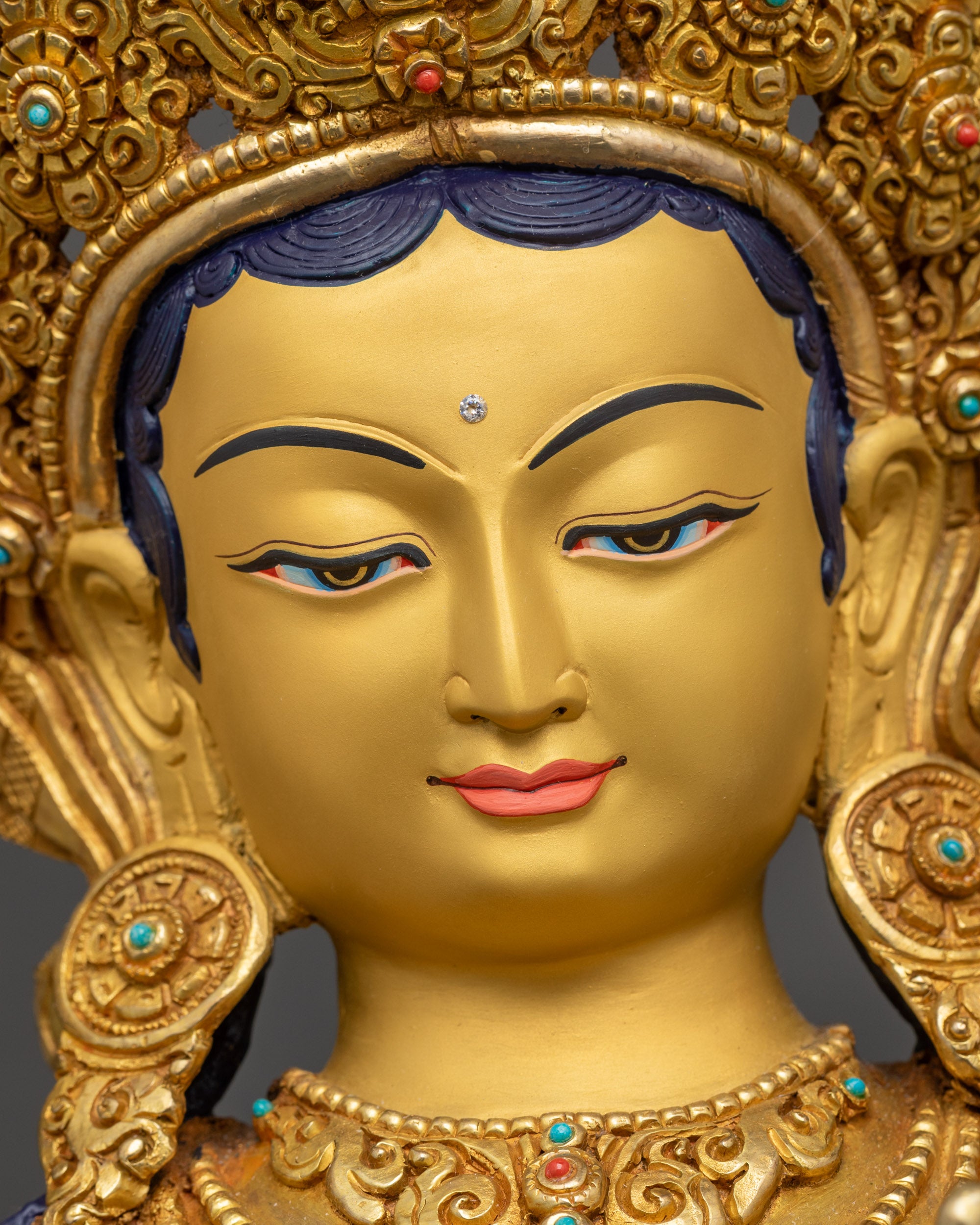 Detailed close up face of Green Tara with serene expression and five-jeweled crown