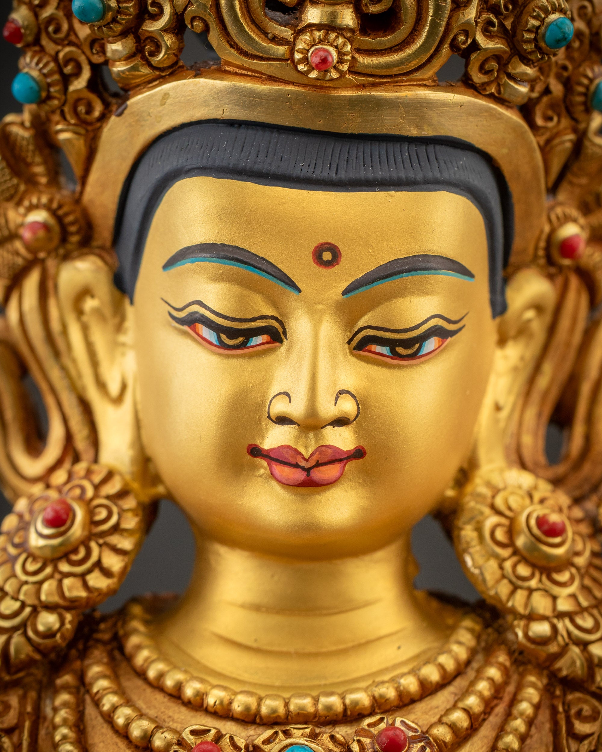 Detailed close up face of Maha Manjushri statue showing crown, jewelry, and serene expression