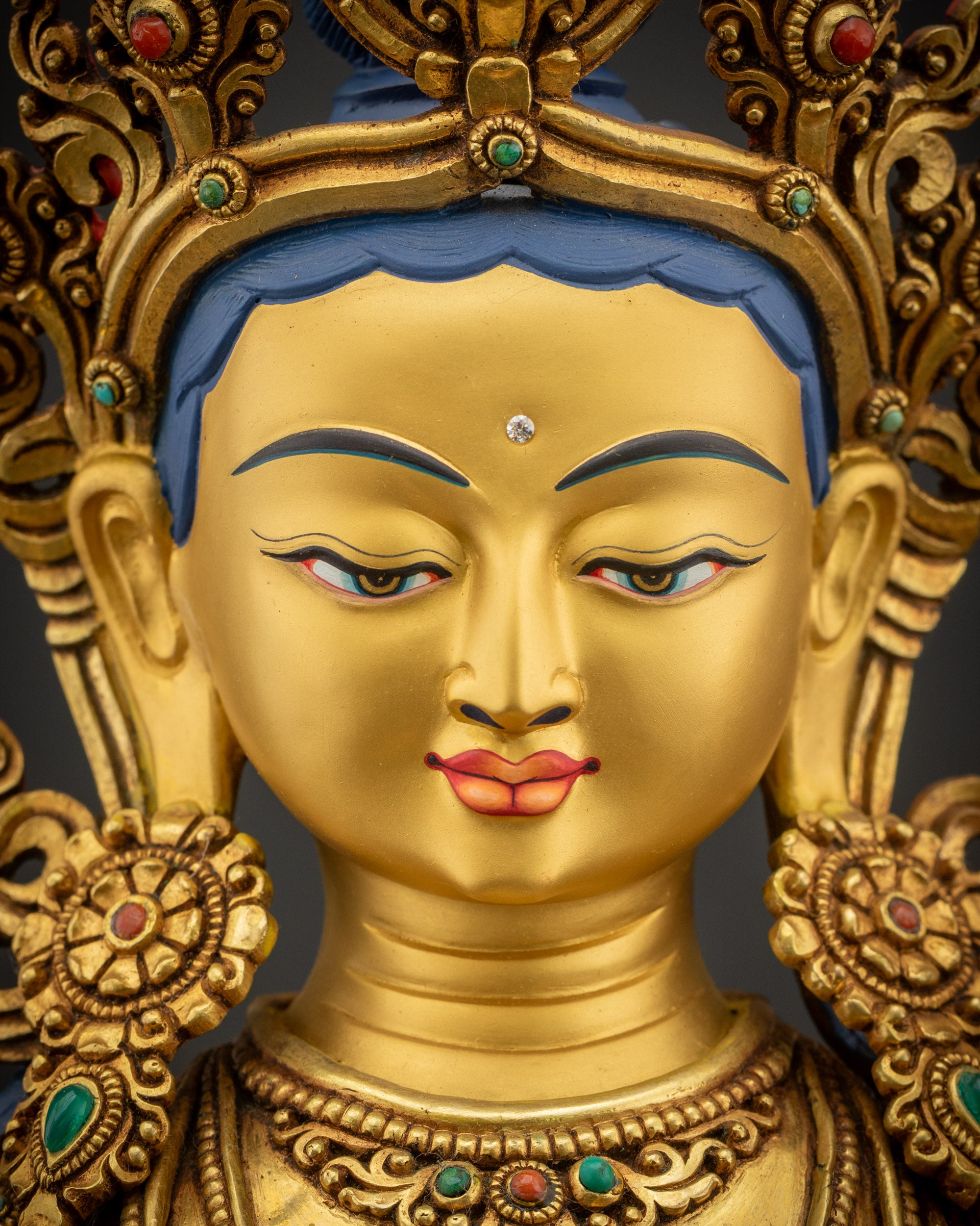 Detailed close up face of Manjushri Statue with radiant gold-gilded Gaze