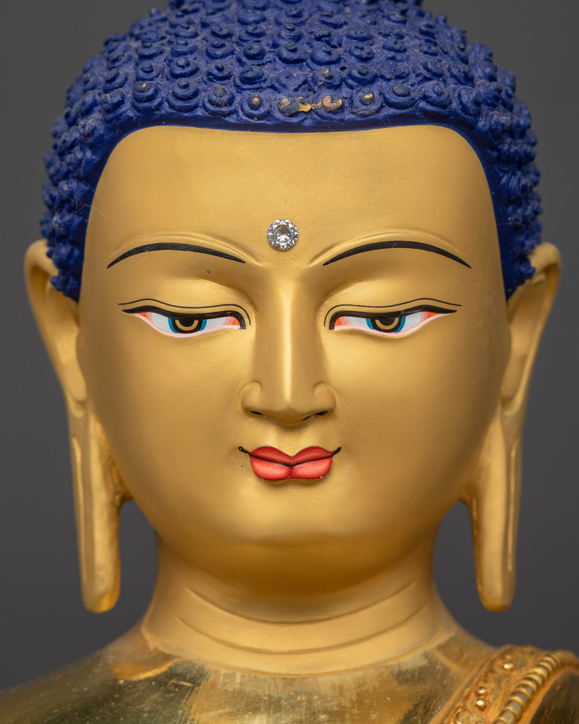 Detailed close up face of Shakyamuni Buddha Statue showing serene gaze and gold-gilded face