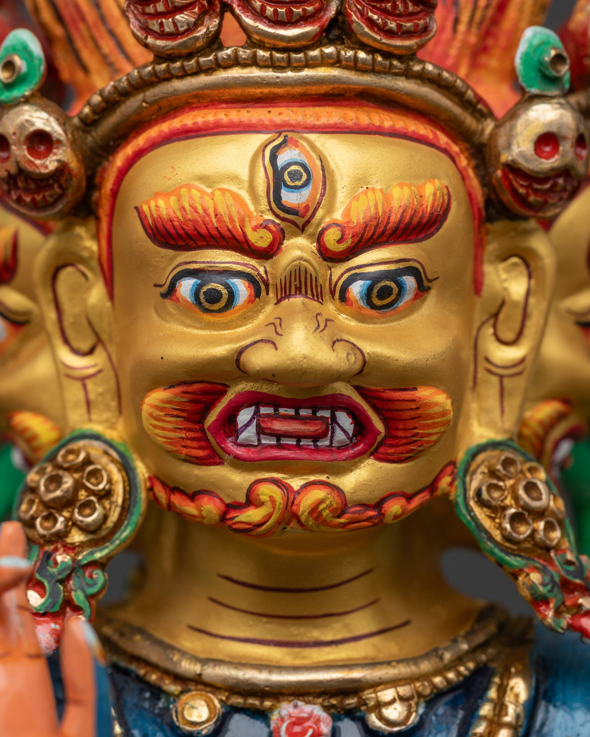 Detailed close up face of Ucchusma Buddhist protector showing gold-gilded expressions
