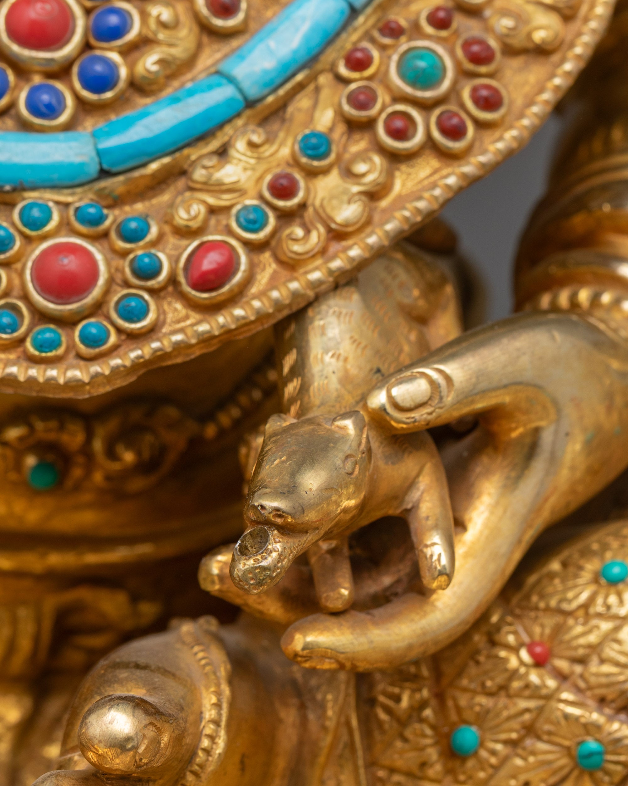 Detailed close up of Dzambhala holding gem-spouting mongoose with intricate carvings