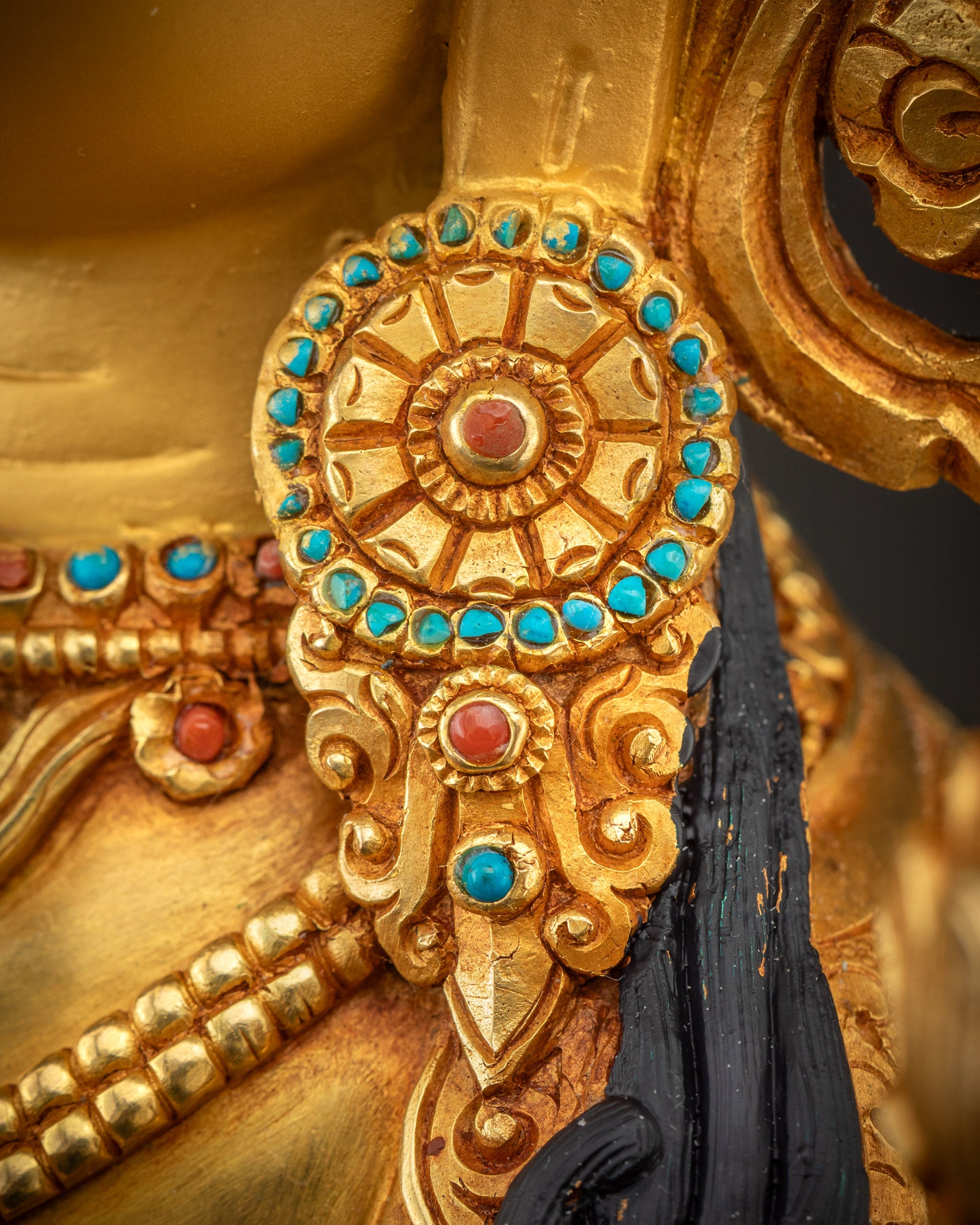 Detailed close up of Green Tara statue earrings with gold and semi-precious stones