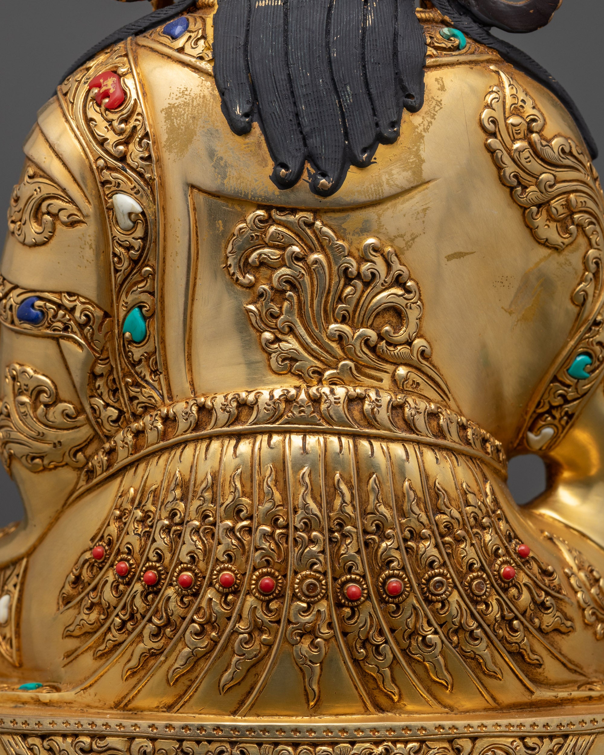 Detailed close up of Guru Rinpoche statue showing intricate robe patterns and motifs