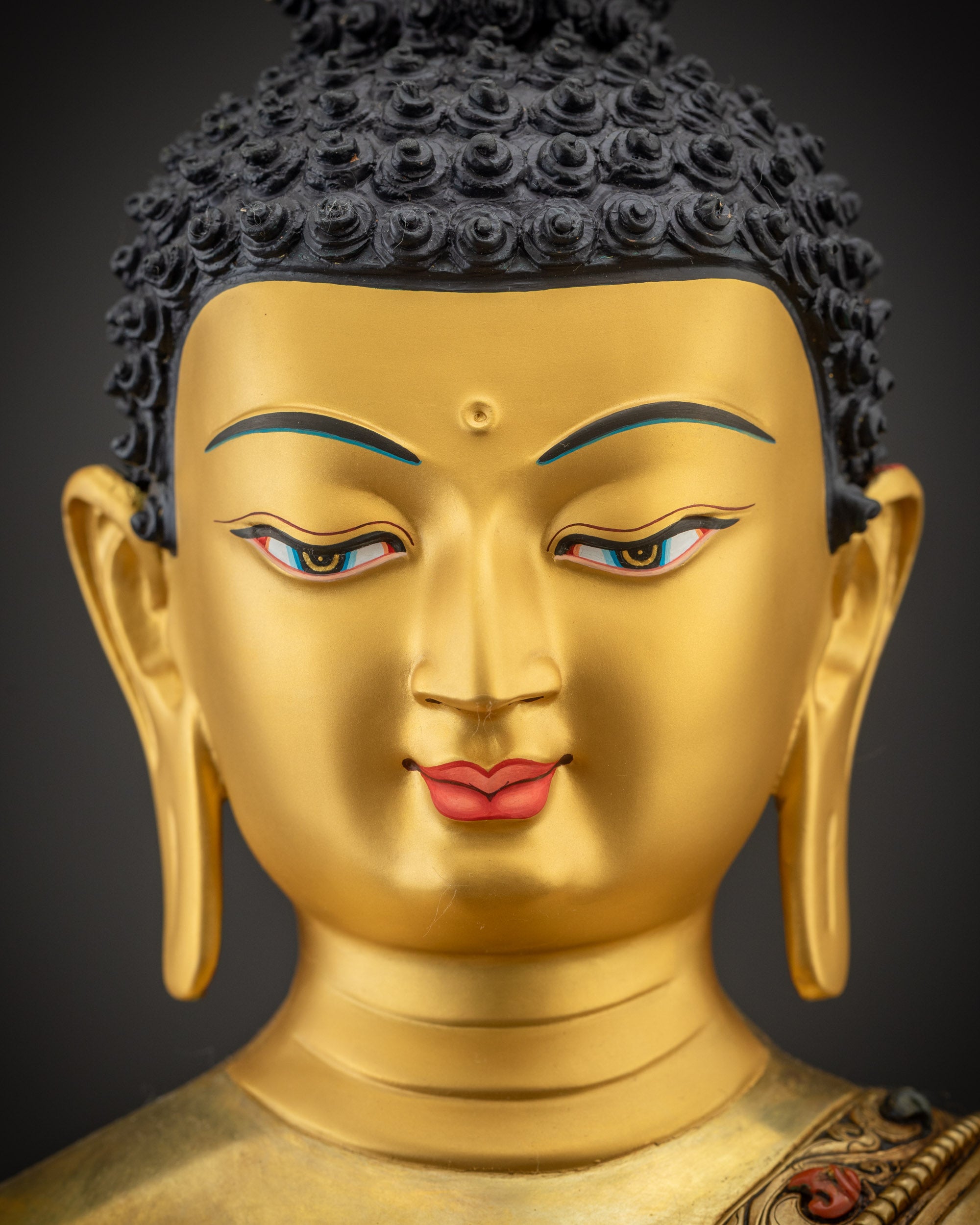 Detailed close up of Shakyamuni Buddha face showing gold gilded glow and calm features