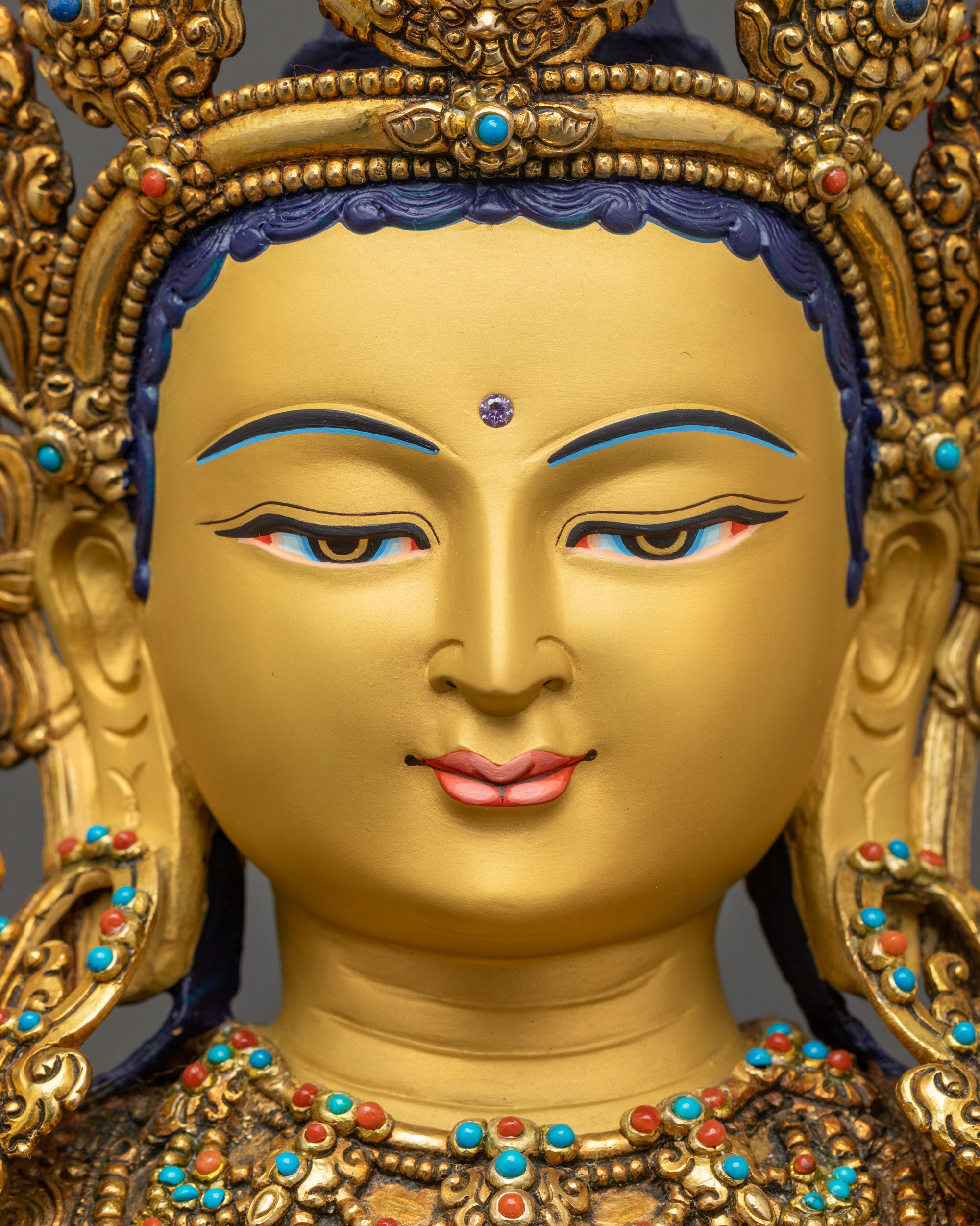 Detailed close up of face Maitreya Buddha with serene expression and gold gilding