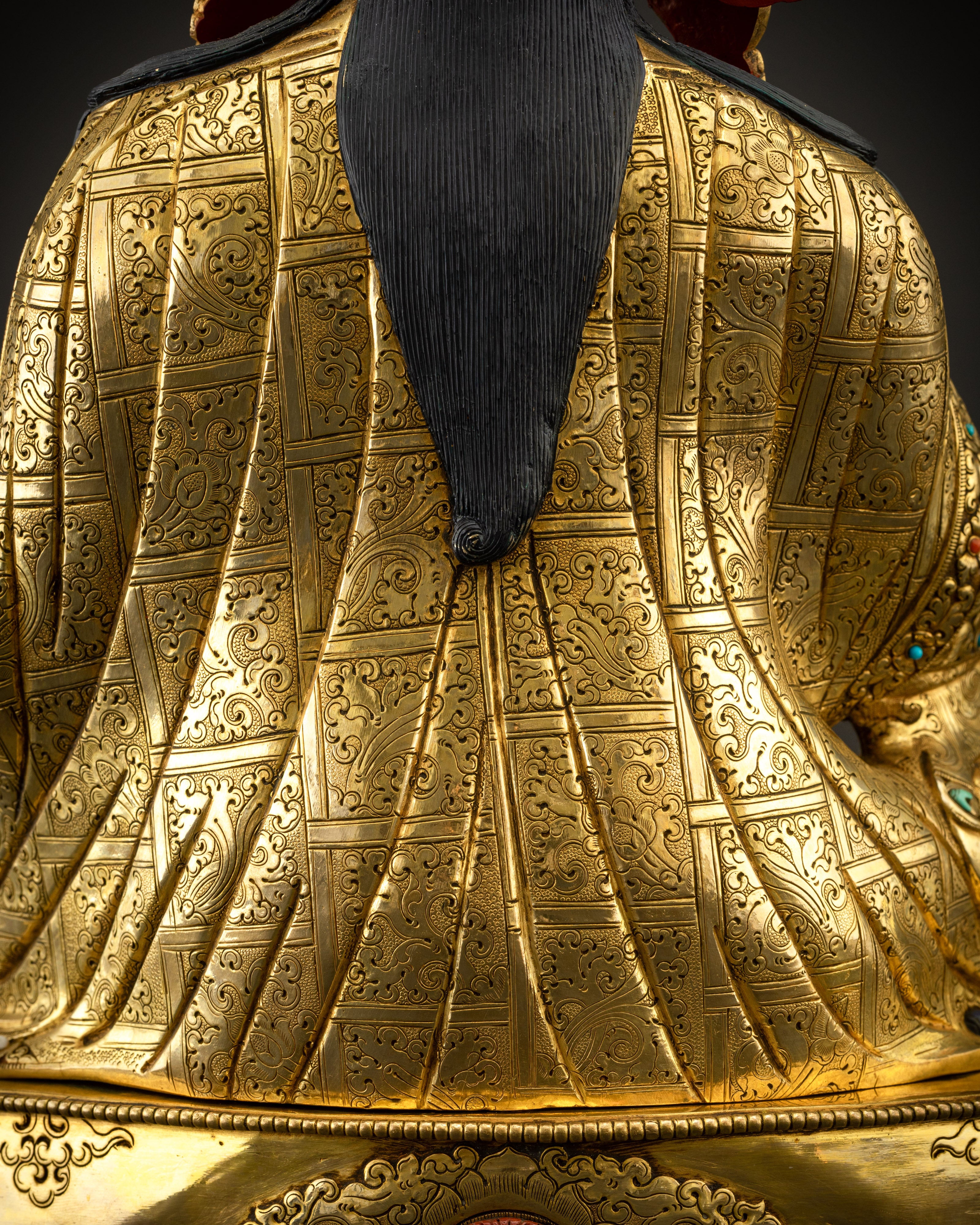 Detailed close up of kasaya robe showing intricate carving and gemstone accents
