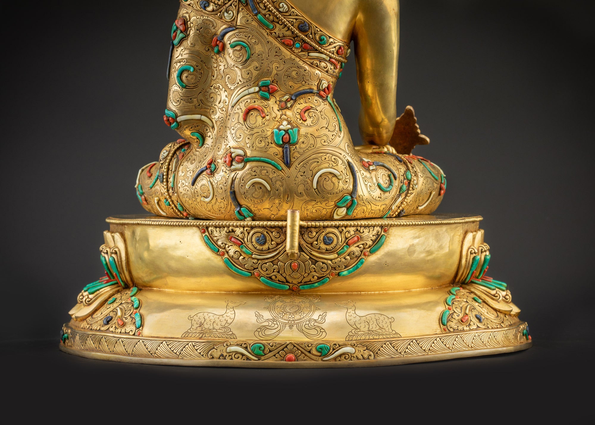 Detailed landscape shot back of Medicine Buddha seated on lotus showing dharma wheel carvings