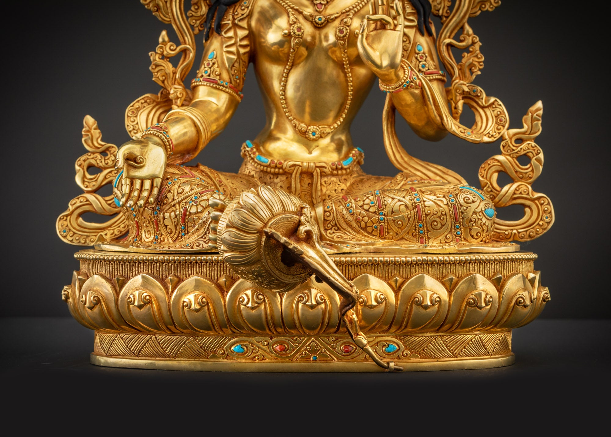 Detailed landscape shot front of Green Tara statue seated on lotus seat in royal ease