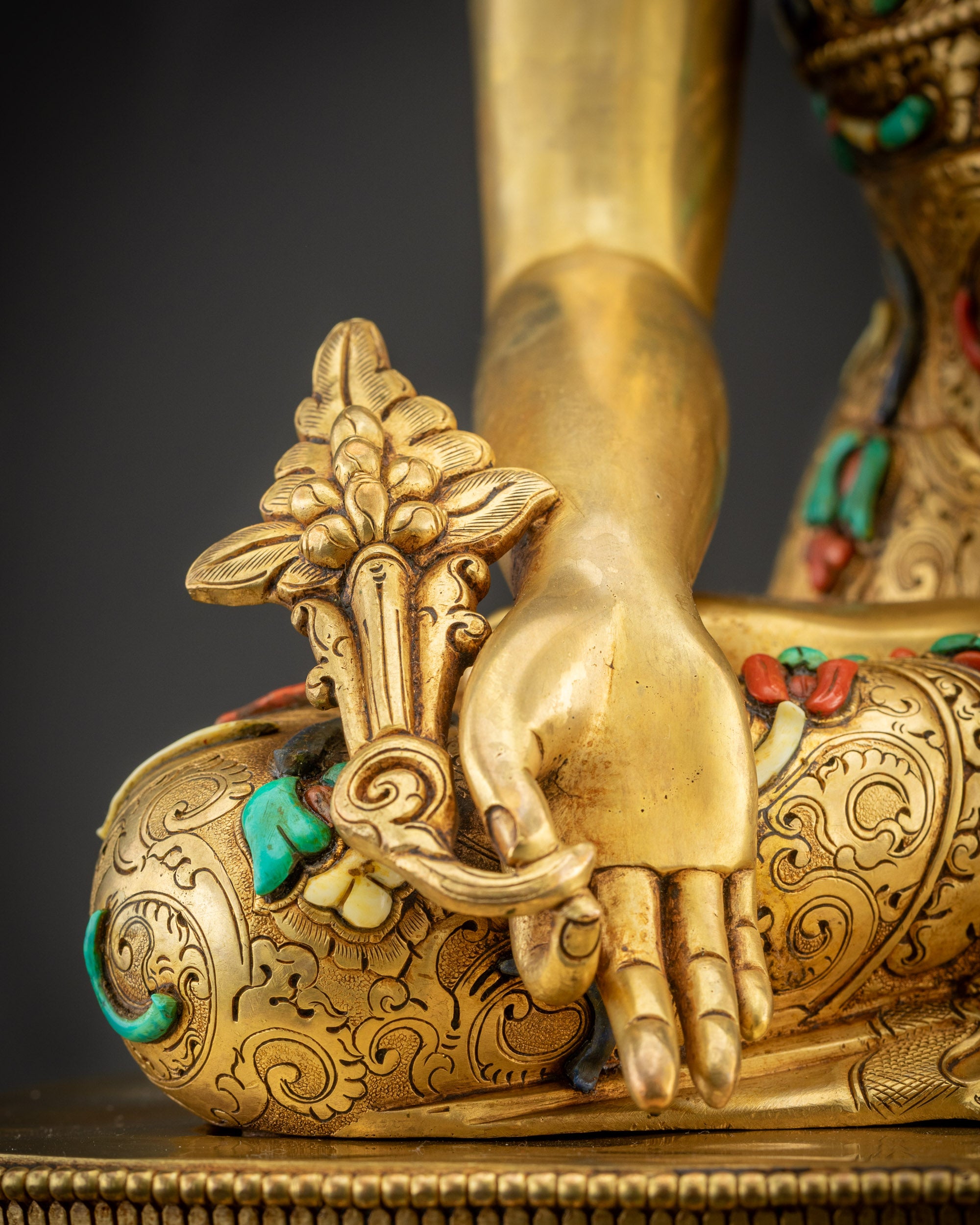 Detailed shot of Medicine Buddha holding myrobalan stem with gold-gilded texture and stones