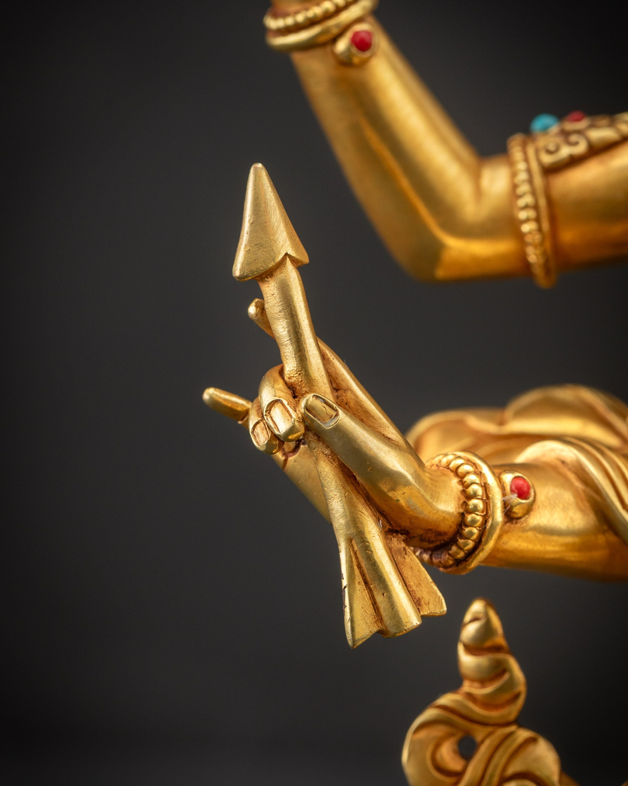 Detailed shot of arrow in Maha Manjushri statue hands highlighting gold fire-gilded and carved design