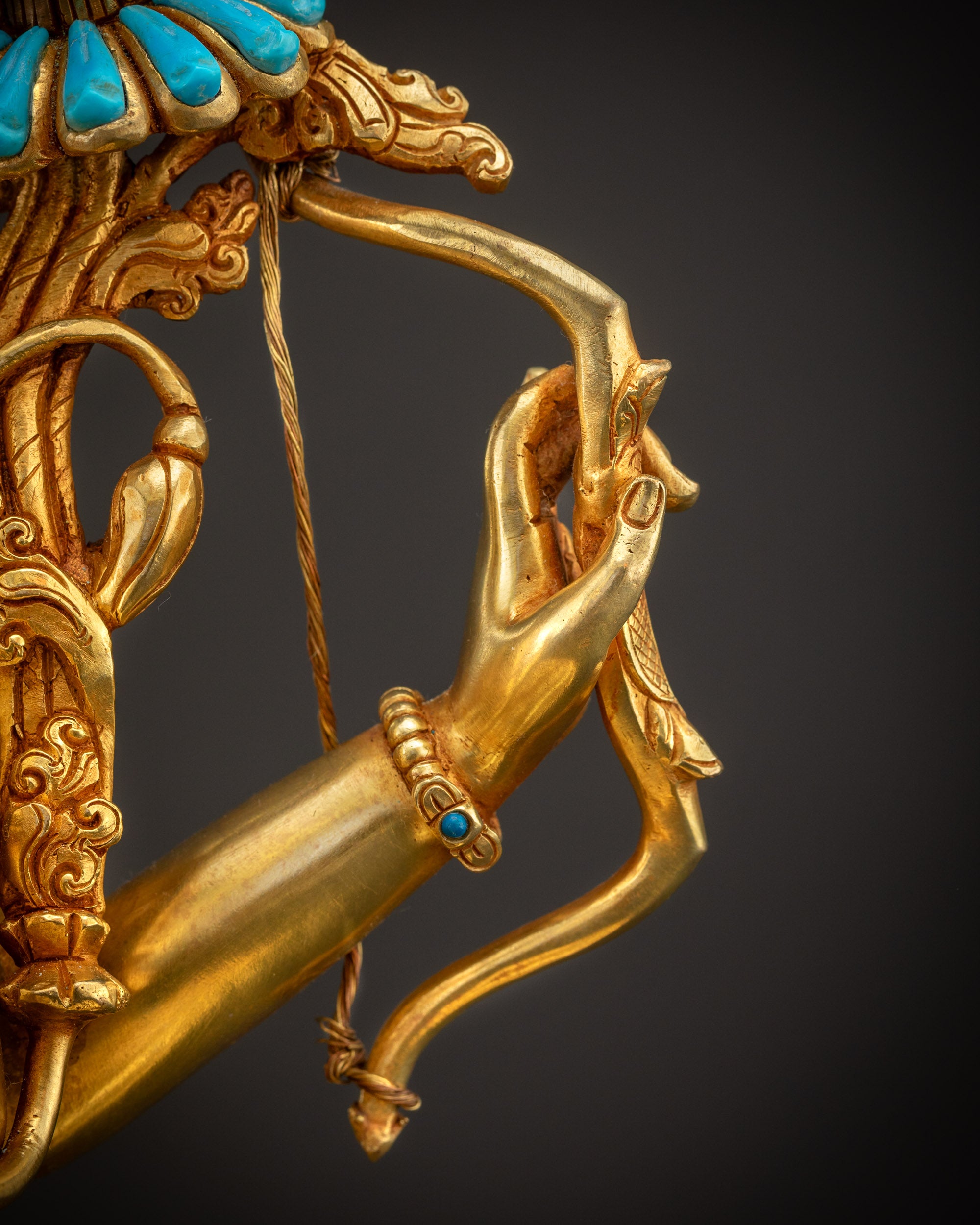 Detailed shot of bow held by Maha Manjushri statue showing intricate carvings and golden shine.