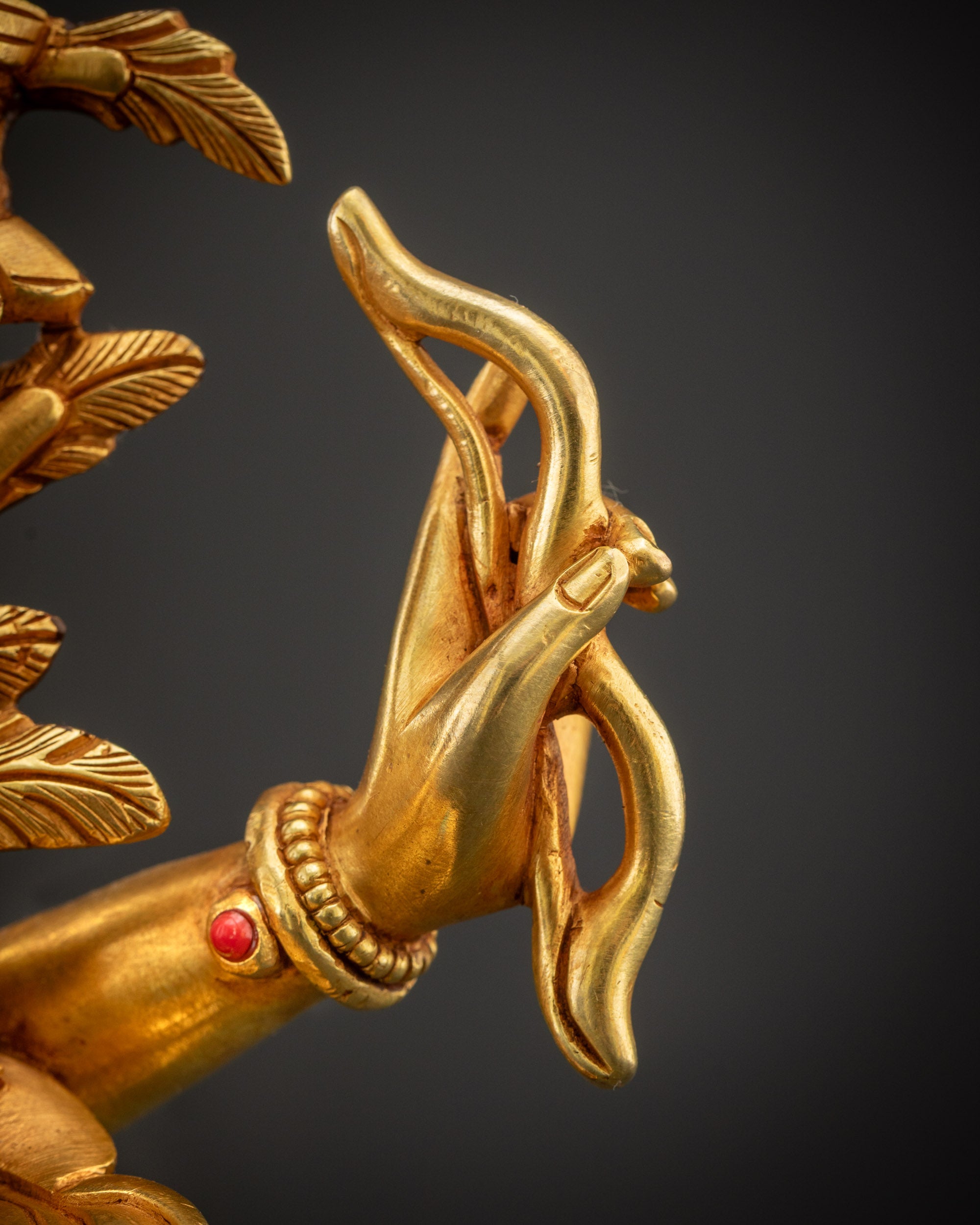 Detailed shot of bow of Maha Manjushri statue showing curved shape and precise gilded carving