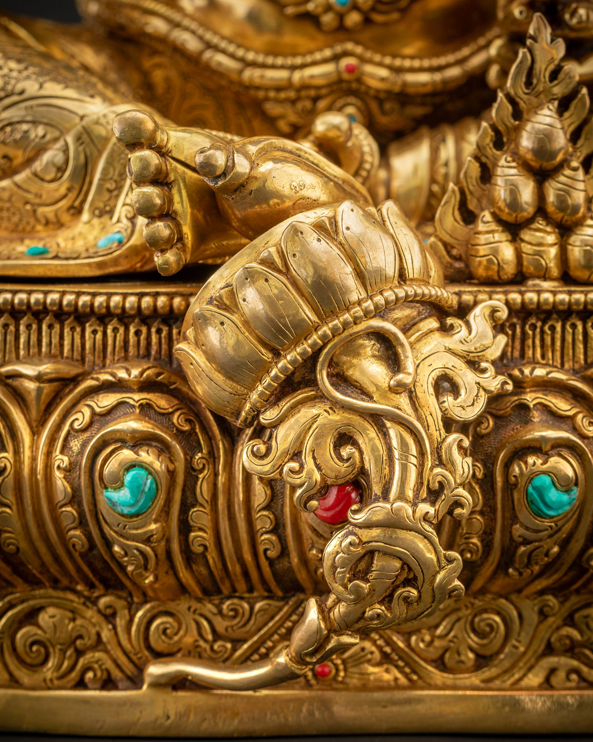 Detailed shot of lower robe of Dzambhala statue showing folds and semi-precious stones
