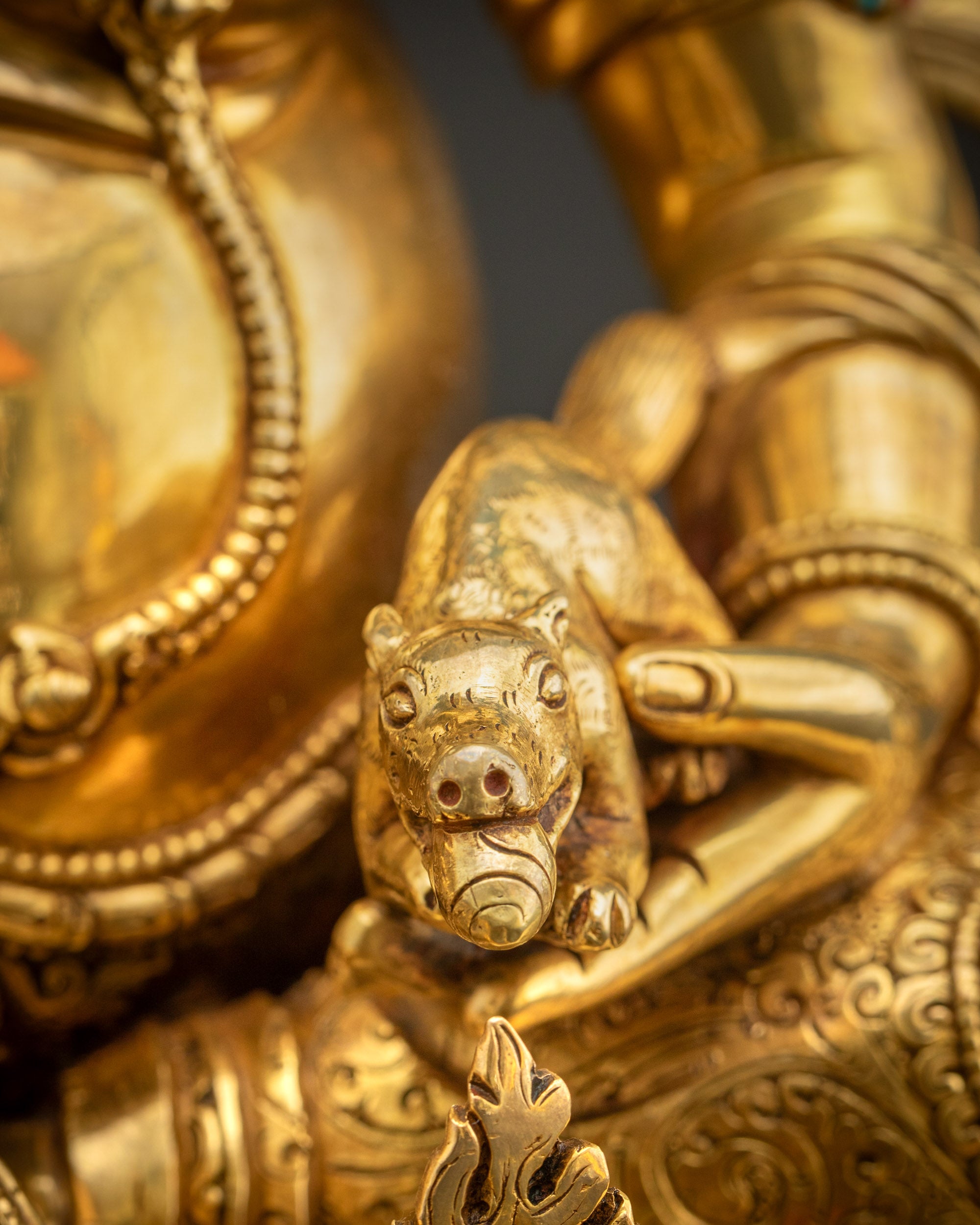 Detailed shot of mongoose of Dzambhala statue spouting precious gems