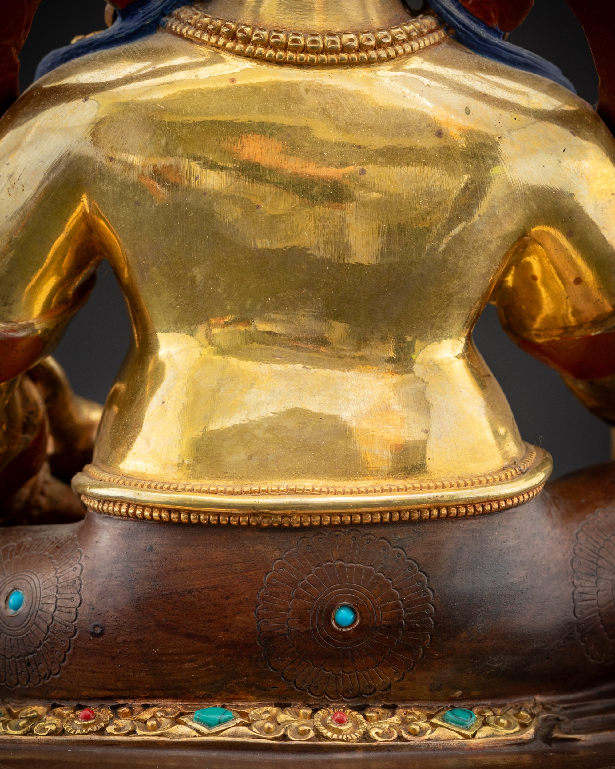 Detailed shot of robe and semi-precious stones on Dzambhala gold-gilded statue
