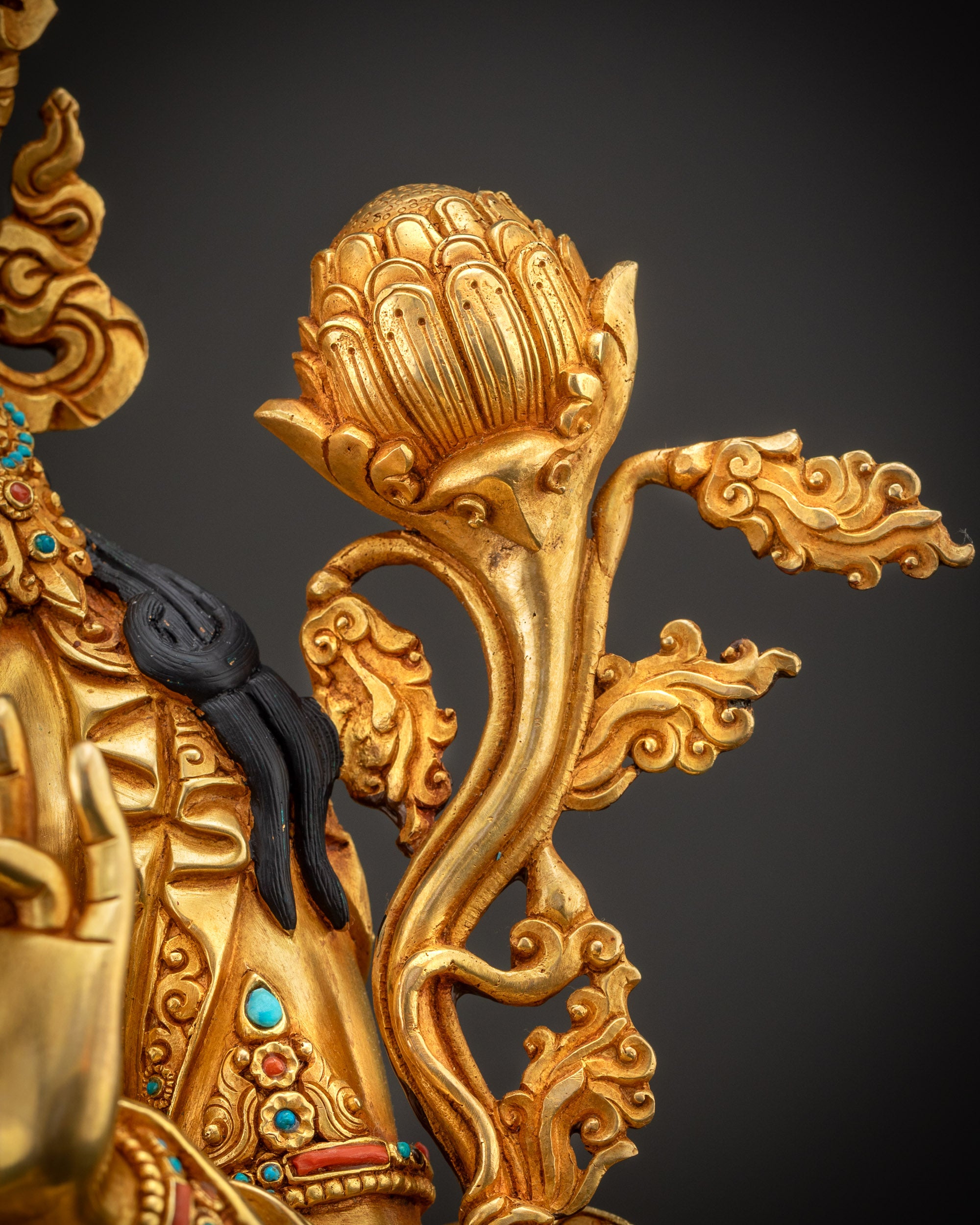 Detailed shot of utpala flower on Green Tara statue with gold accents