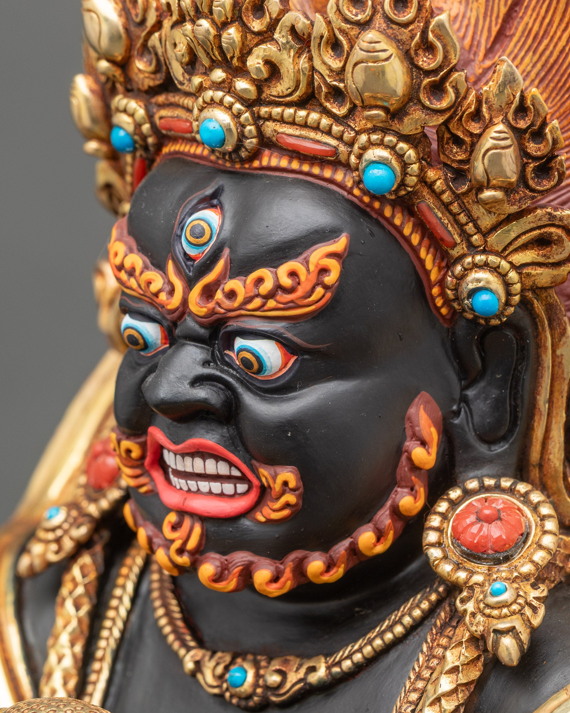 Detailed side close up – Side close-up of Black Dzambhala statue, ornate crown and flaming mandorla visible