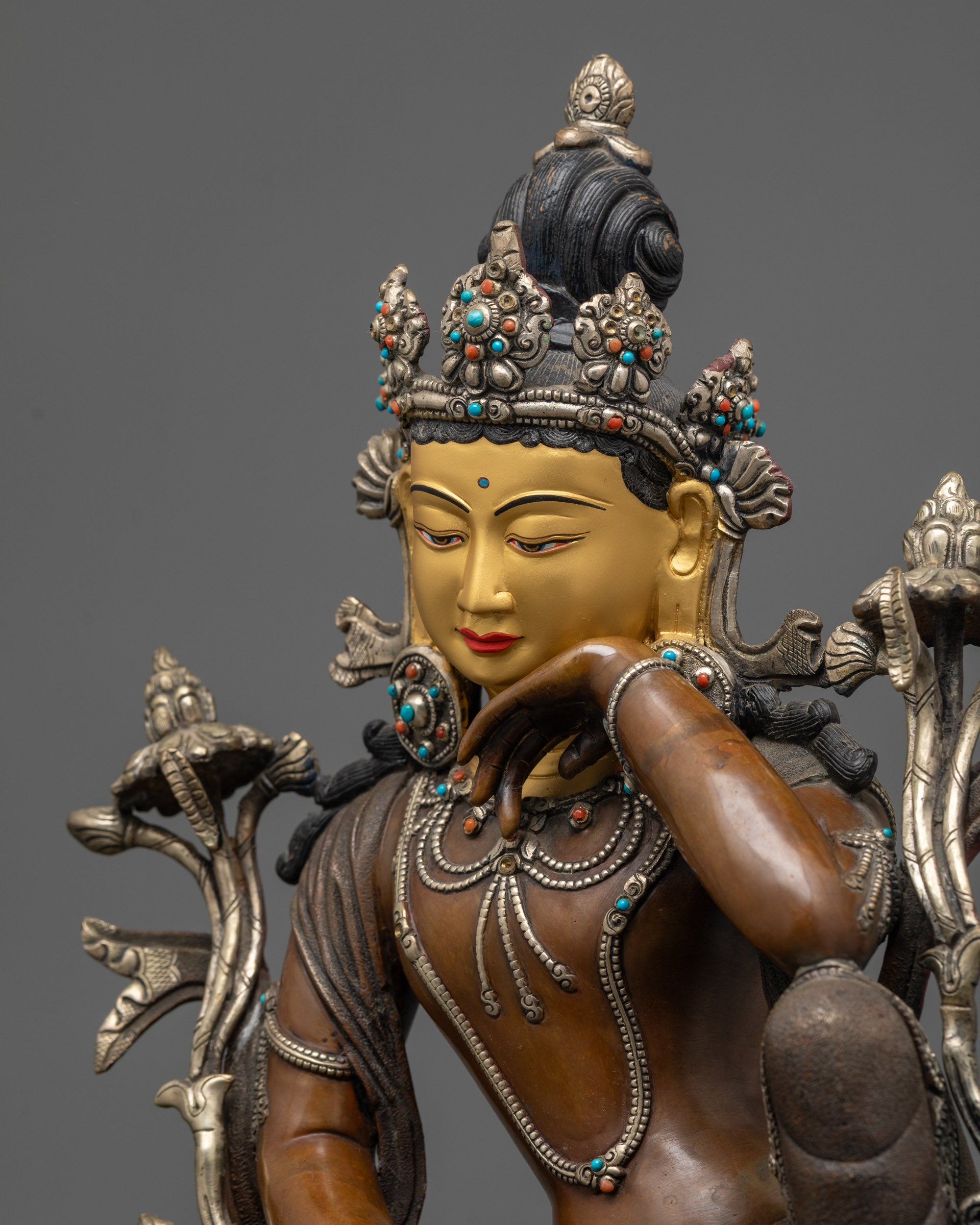 Detailed side view of Chenrezig statue showing silver-plated robe and patterned garments
