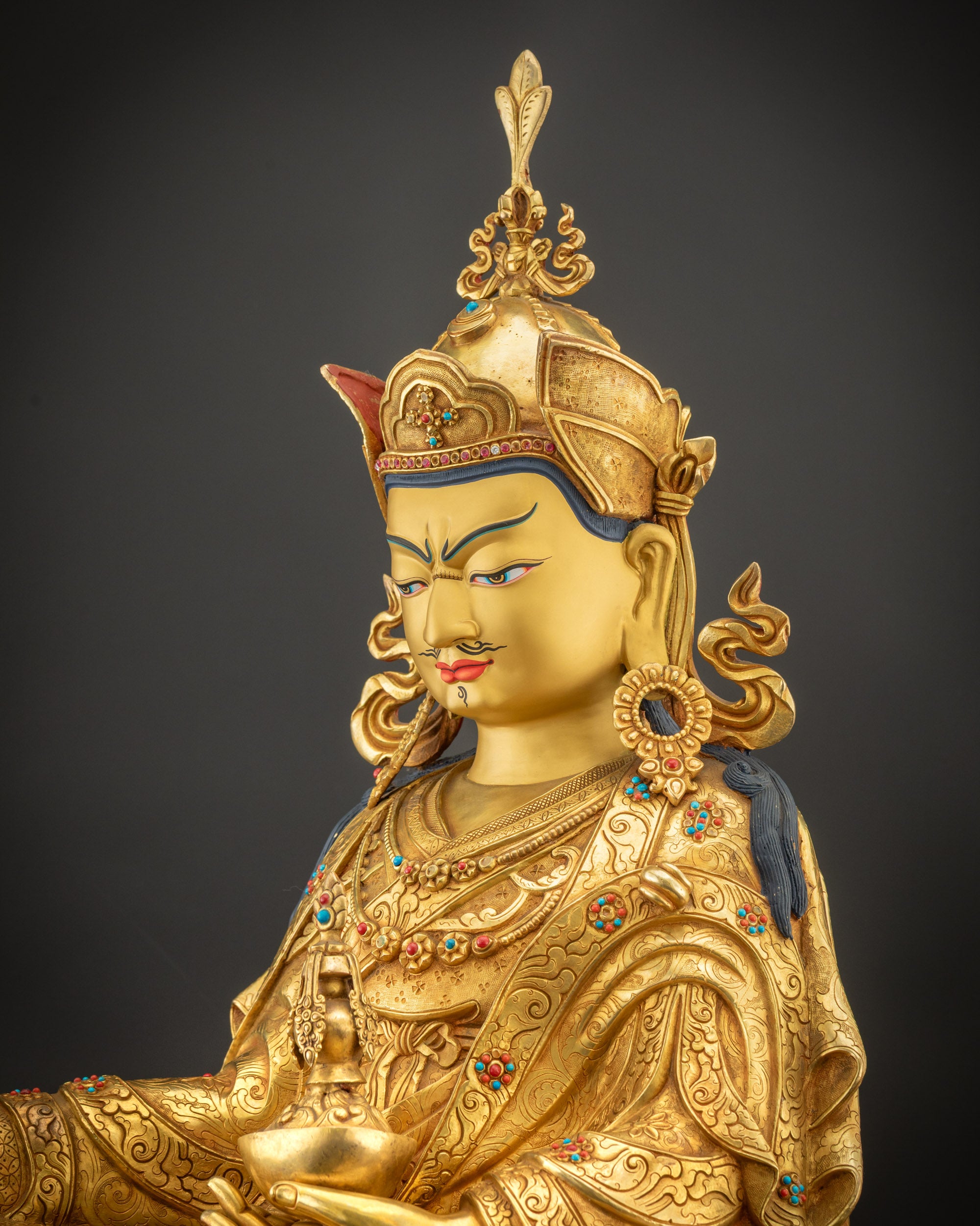 Detailed side view of Guru Rinpoche holding kapala and khatvanga staff