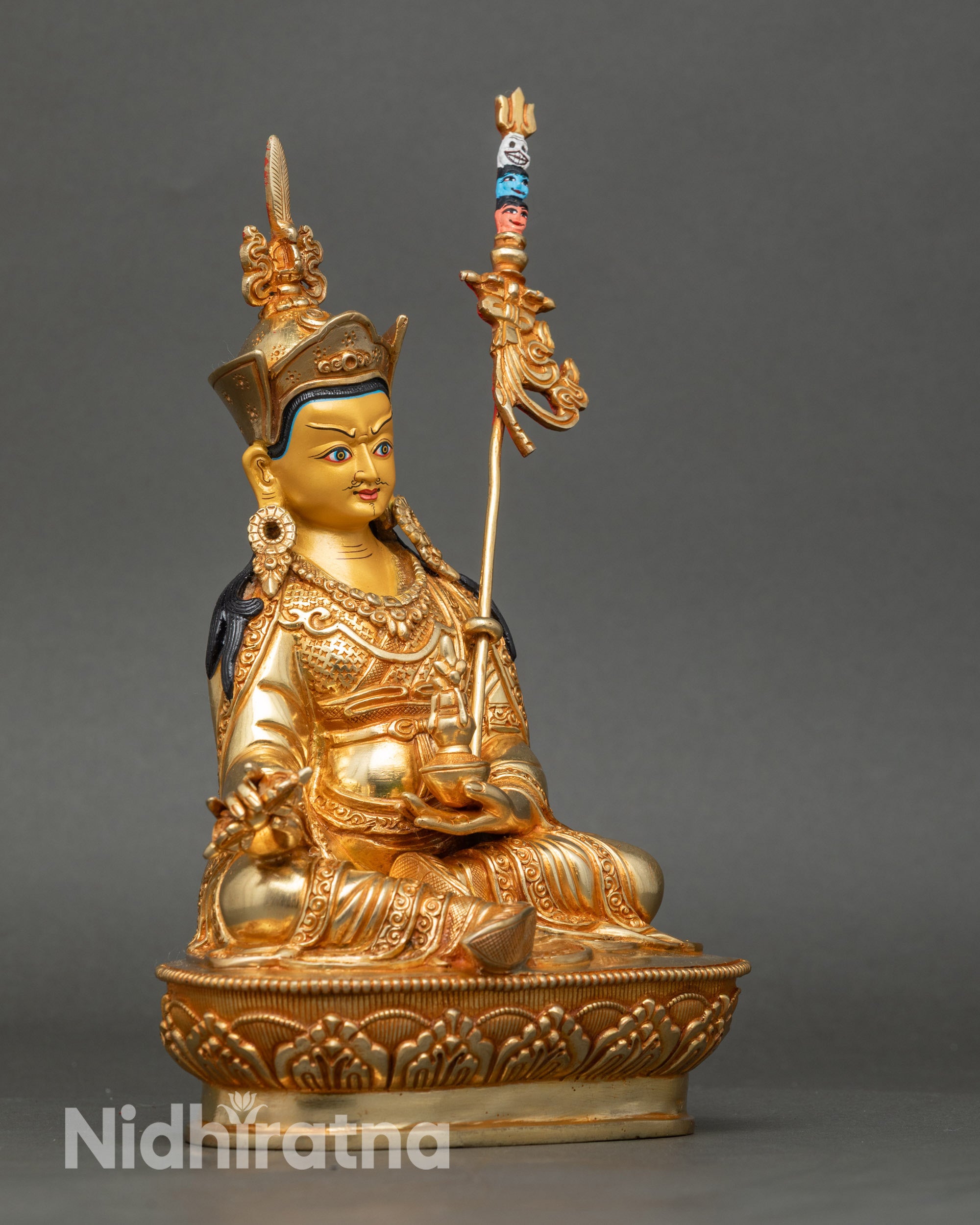 Detailed side view of Lotus-Born Guru statue holding skull cup and vajra