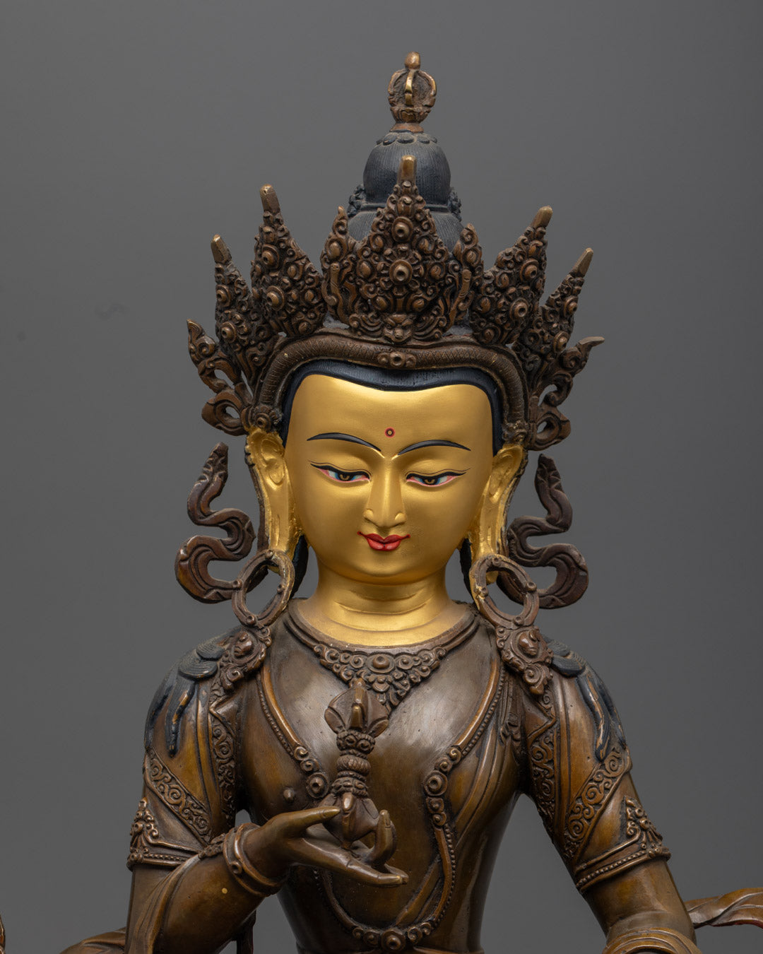 Detailed view of Vajrasattva's serene gold-plated face and hands holding vajra (thunderbolt) and ghanta (bell)